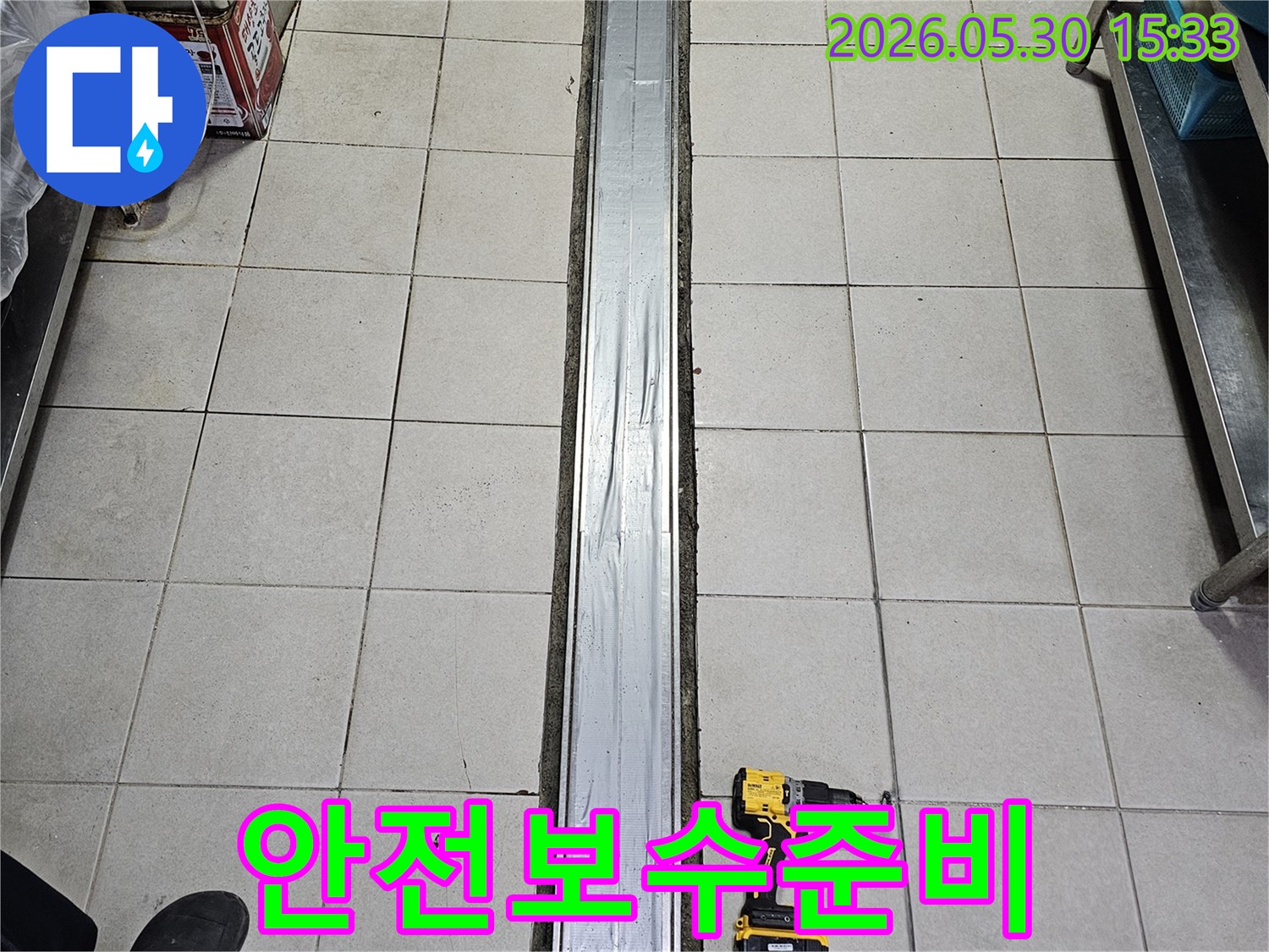 타일 바닥과-배수 트렌치-그리고 작업용 전동 드릴이 놓인-안전한 누수 보수를 위한-준비 현장입니다