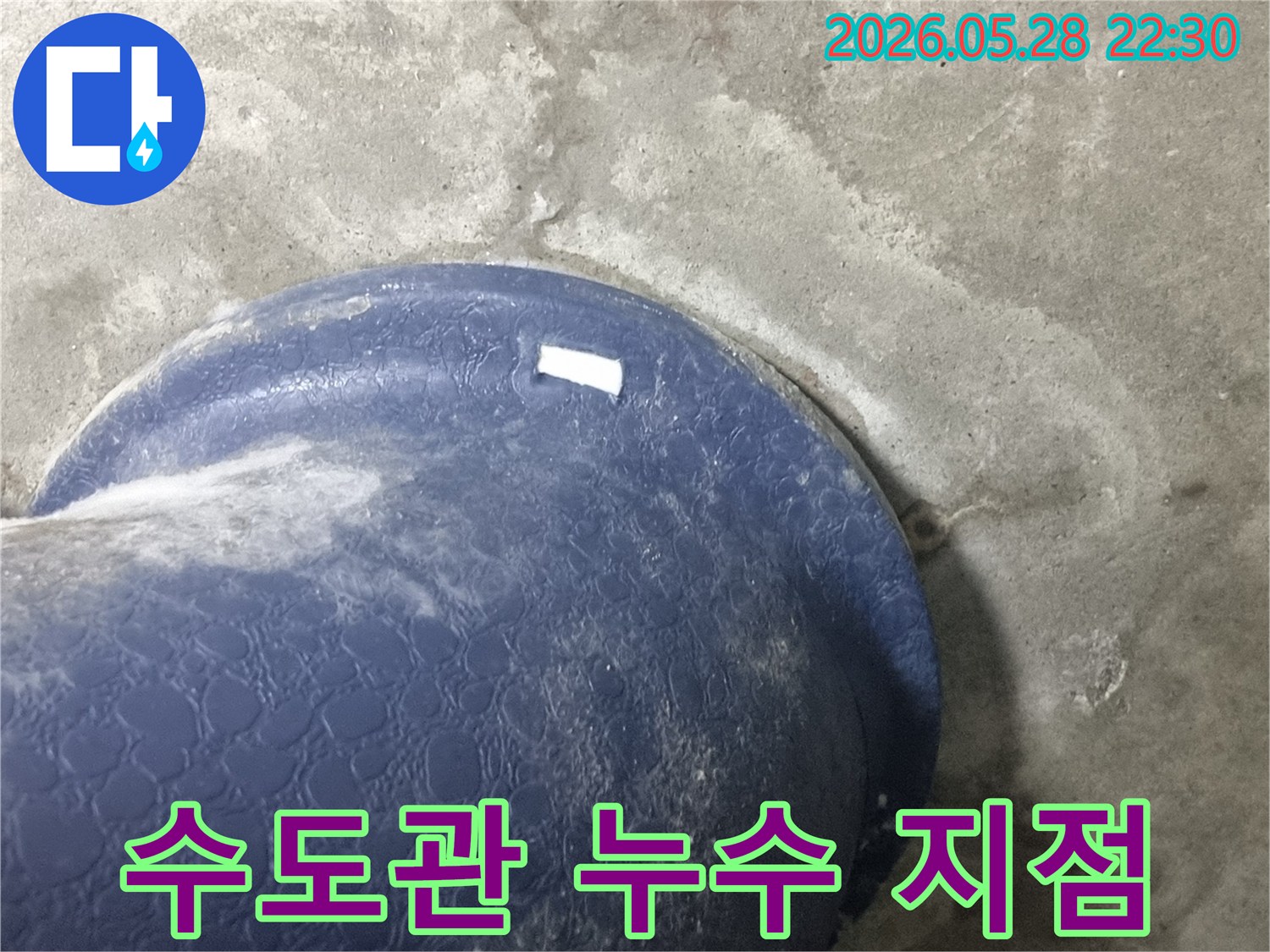 콘크리트 바닥에-매립된-파란색 수도관-주변으로-물이-새어-나와-젖은-모습을-보여주는-현장-사진
