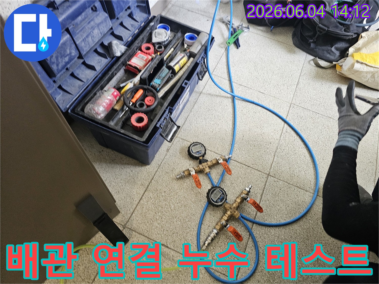 누수-탐지를 위해-배관에-연결된-파란색-호스와-정밀-압력-측정-장비가-설치된-모습입니다.