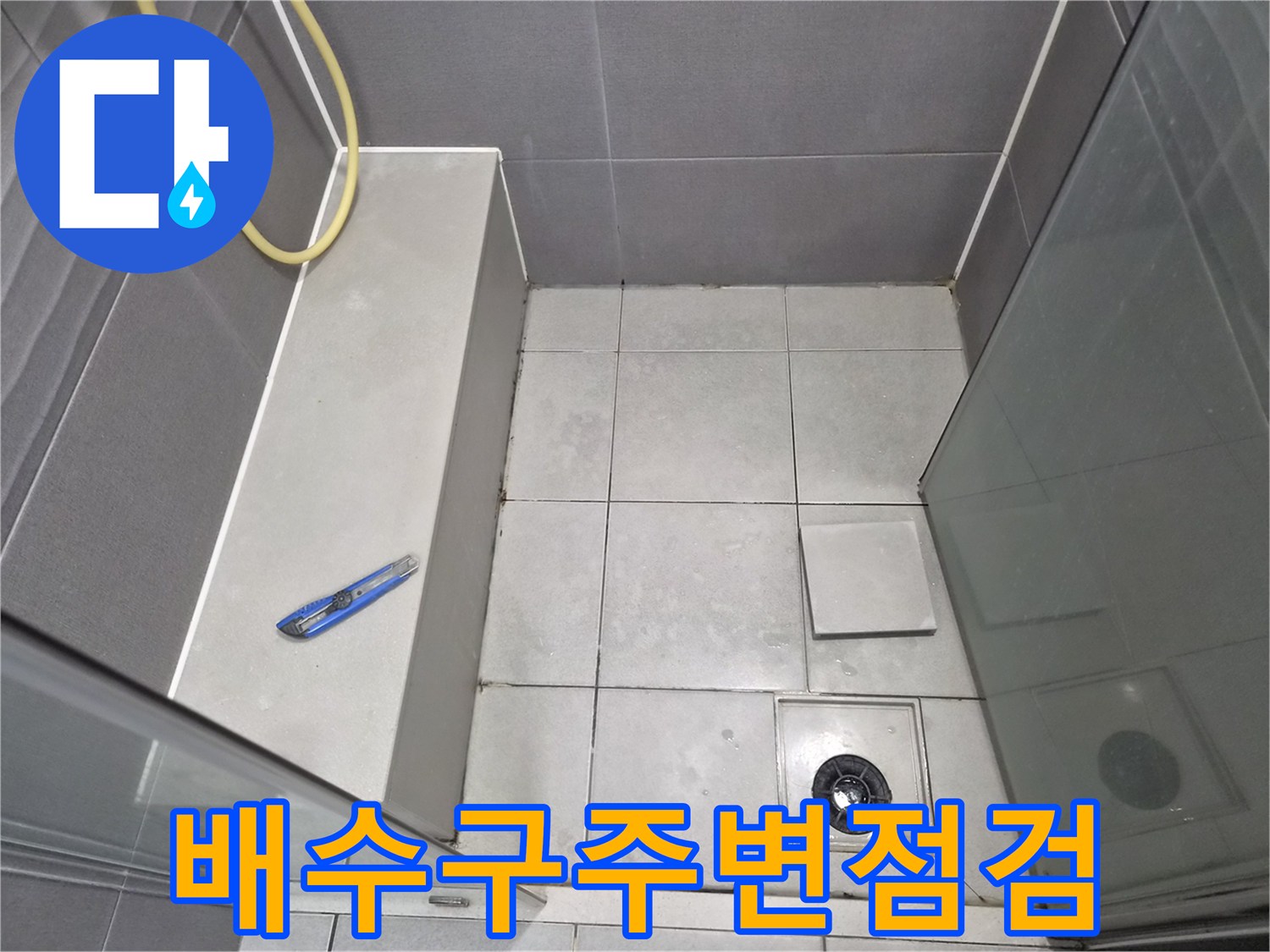 욕실-바닥-배수구-주변의-타일-상태와-줄눈-그리고-누수-점검을-위한-도구가-놓인-현장-사진입니다.