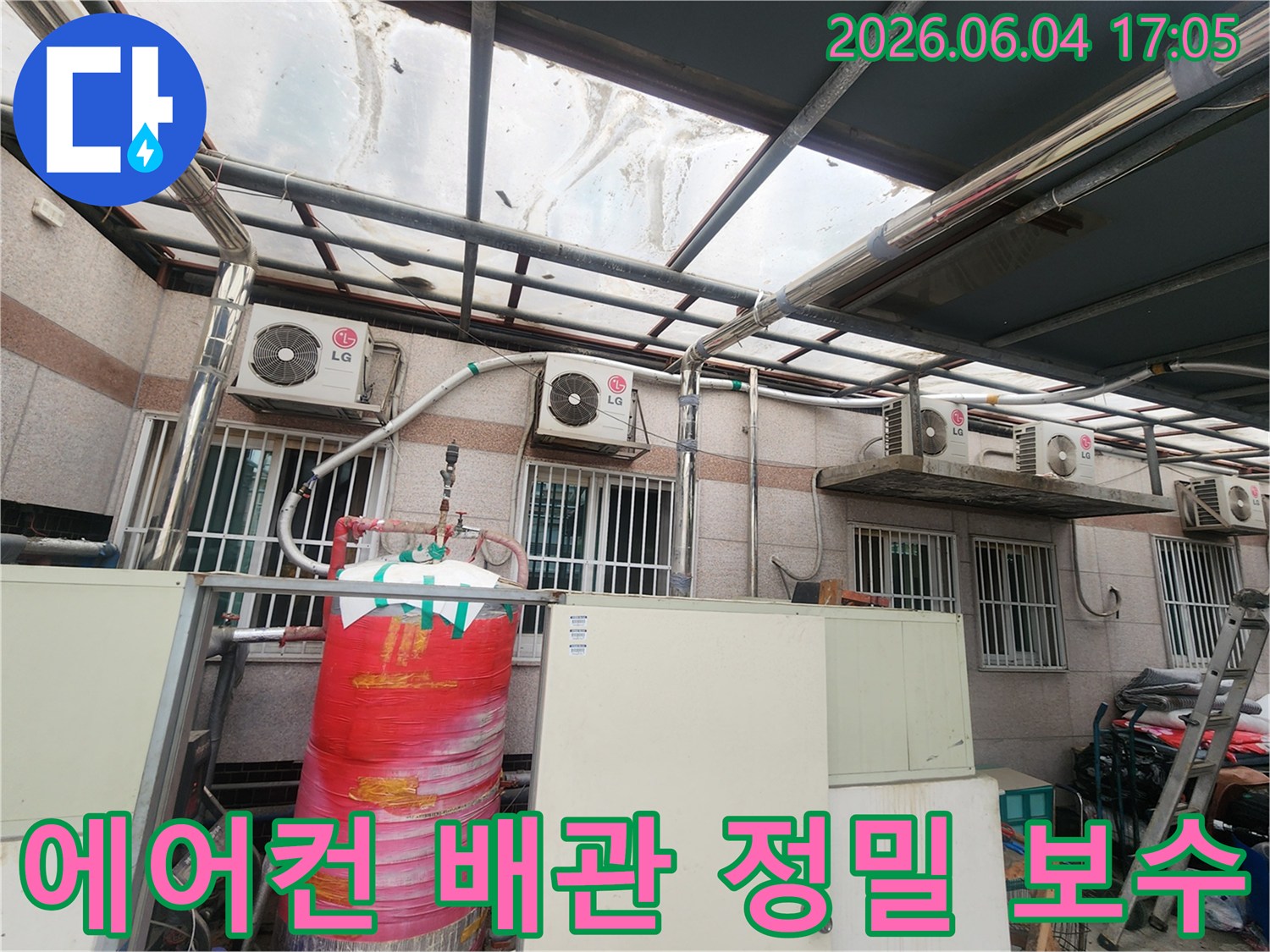 이 이미지는 상가 건물 외벽에 설치된-LG 에어컨 실외기와-그에 연결된 배관들을 보여줍니다