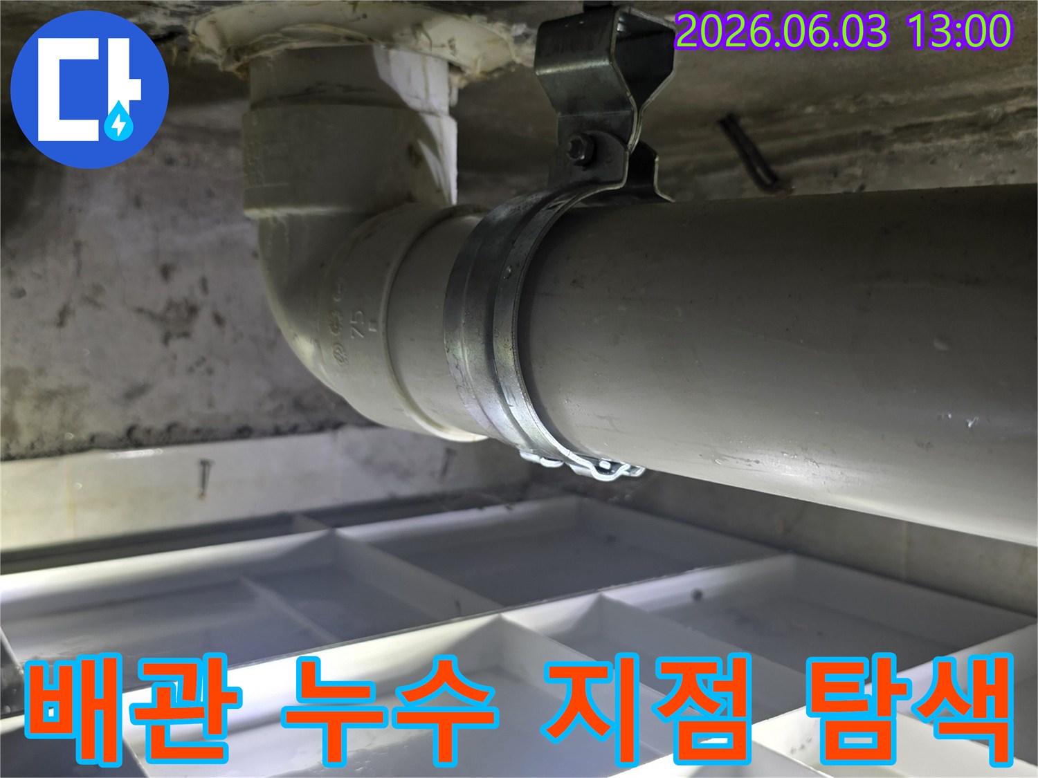 벽면에 고정된 배수관의 연결 부위를-면밀히 관찰하며 누수 지점을 탐색하는 모습입니다