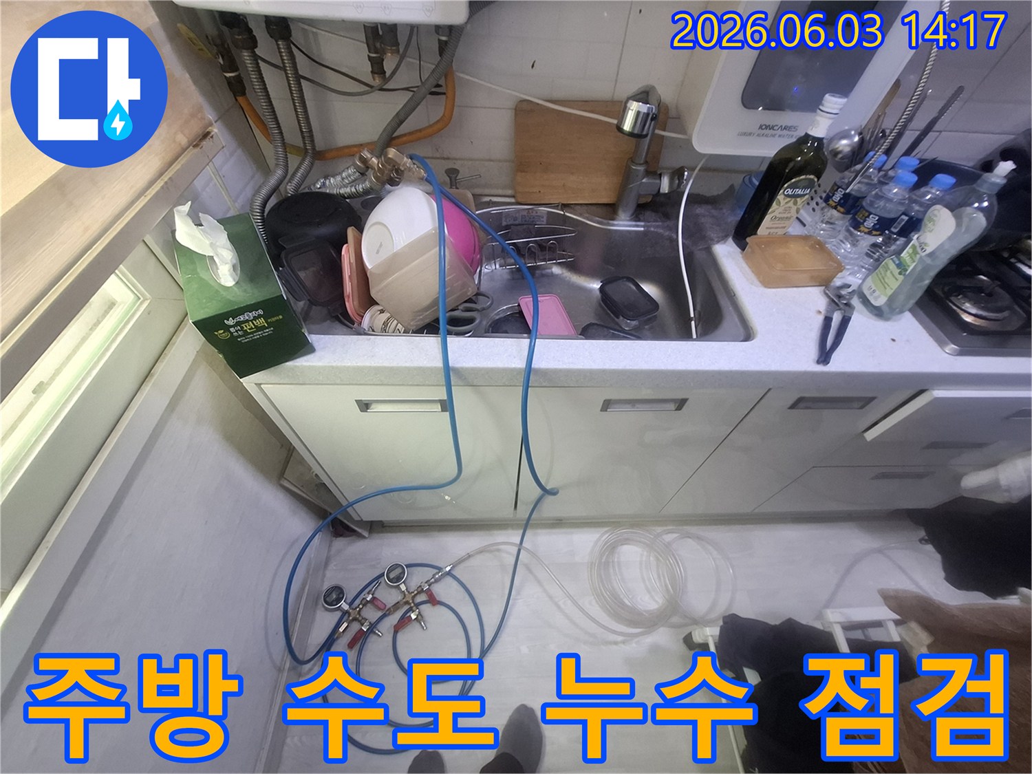 영등포 주방 싱크대 아래-수도 배관에서 발생한 누수를-정확히 찾아내기 위해-압력 테스트 장비를 연결하여-진단하는 현장