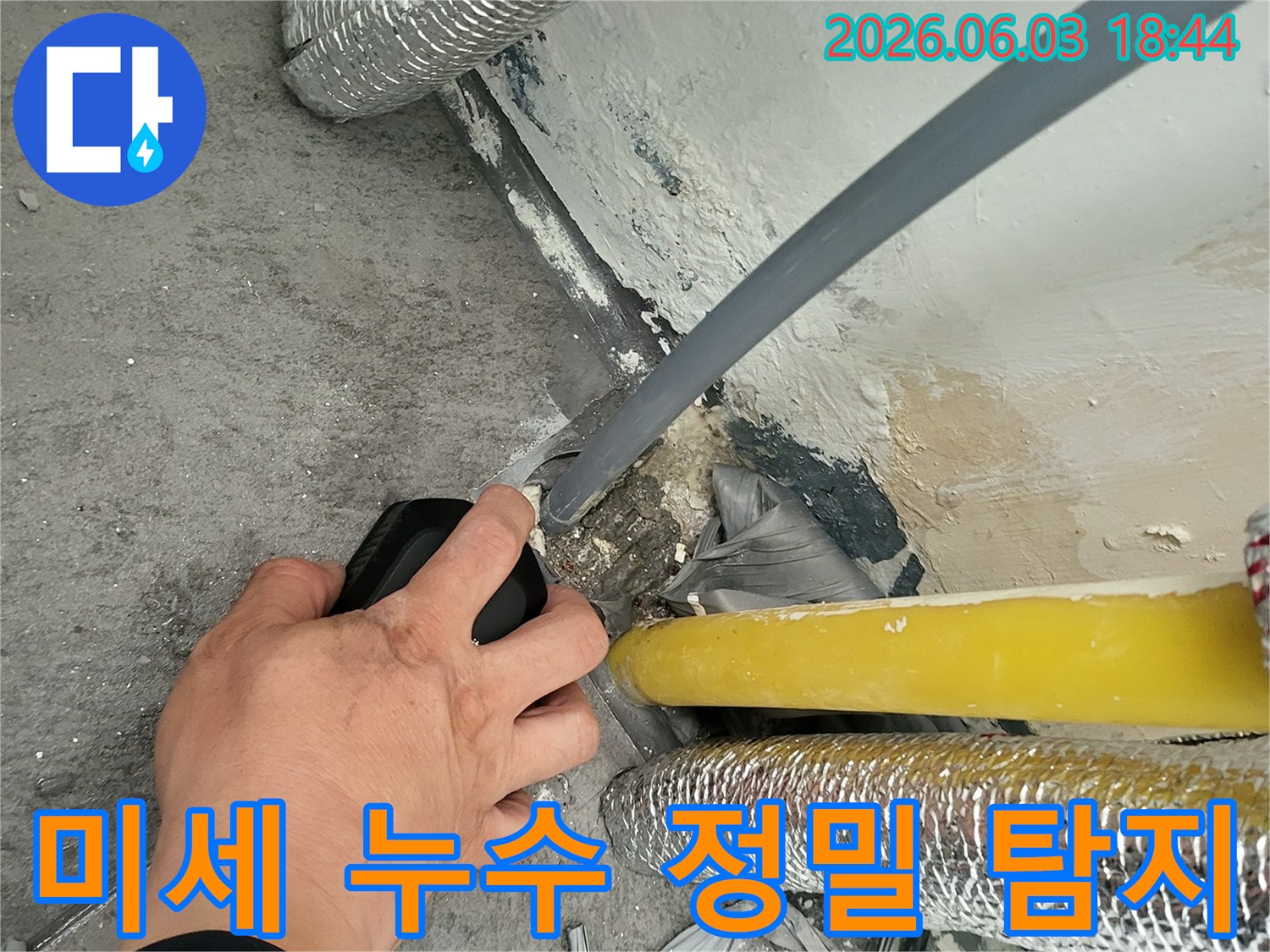 전문가가-벽면-하단의-배관에서-발생한-미세-누수-지점을-탐지기로-정밀하게-확인하는-모습입니다.