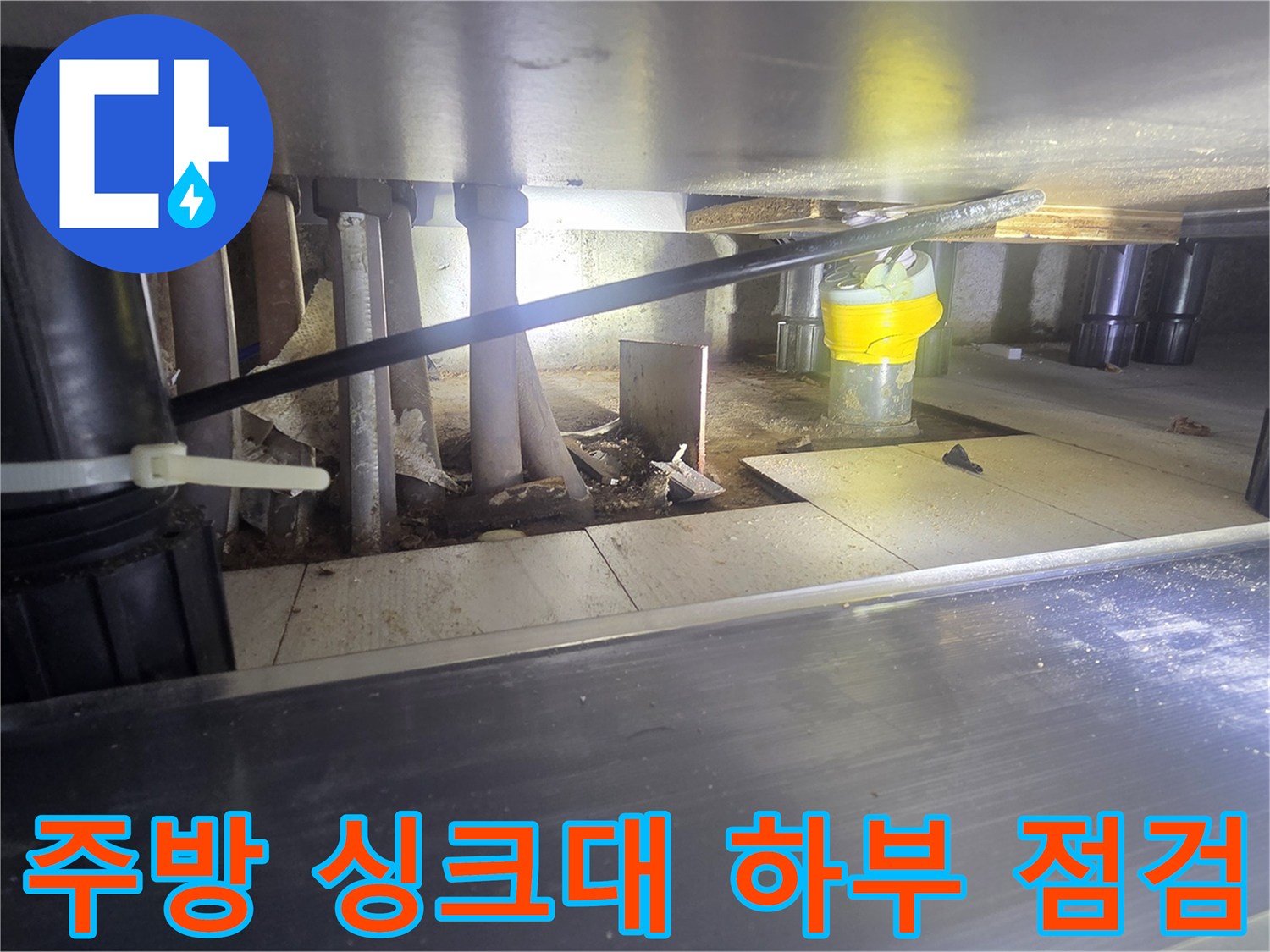 싱크대 아래쪽의 다양한 배관들과 연결 부품들을 촬영한 사진