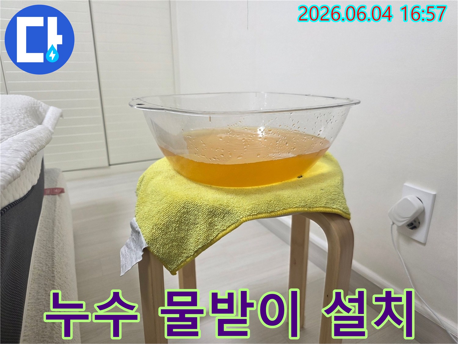누수 발생 시-바닥 손상을 막기 위해-설치된 임시 물받이와-그 위에 놓인 노란 수건의 모습