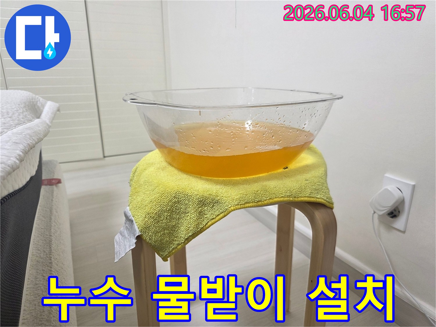 누수 발생 시-바닥 손상을 막기 위해-설치된 임시 물받이와-그 위에 놓인 노란 수건의 모습