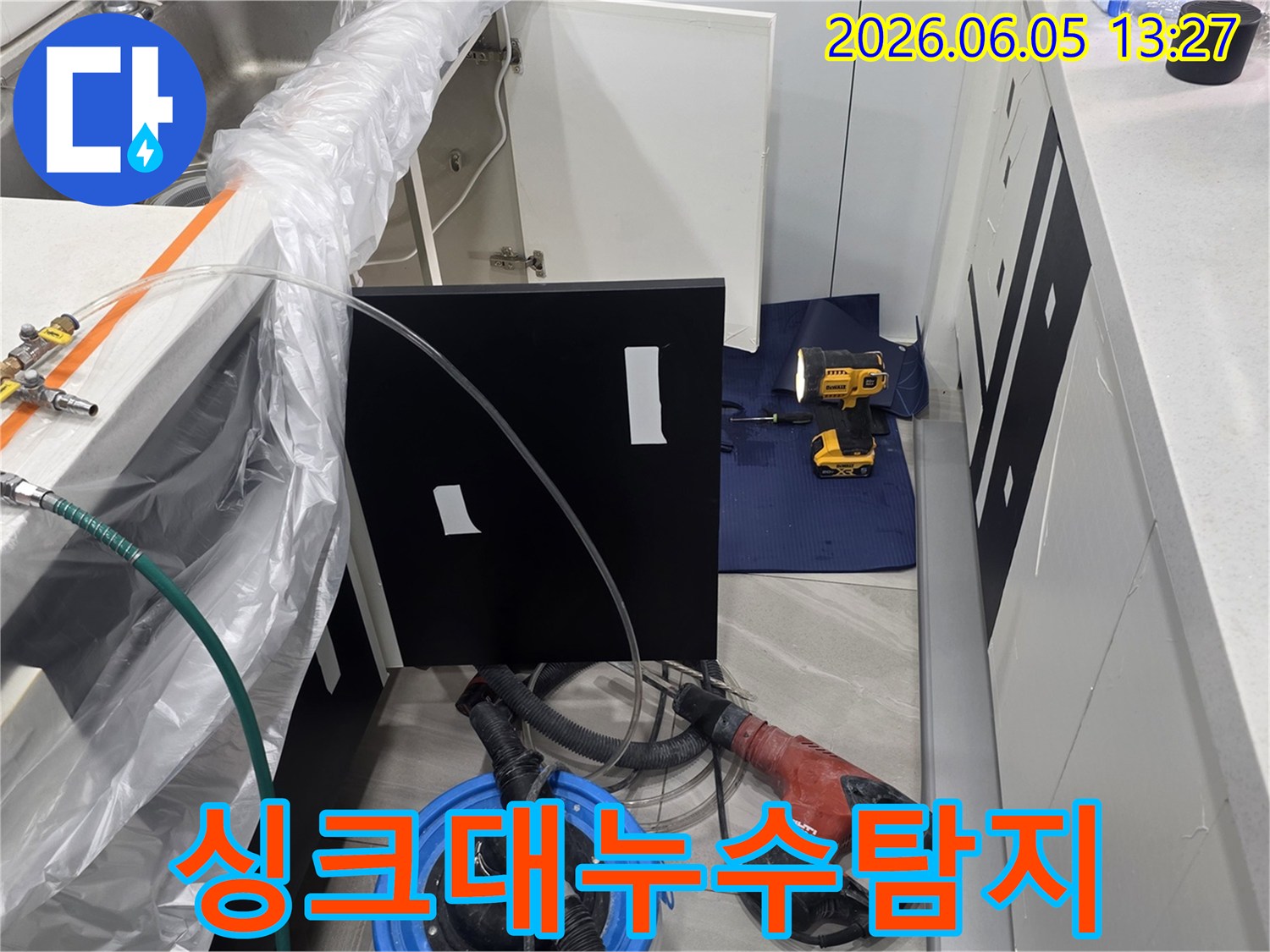 누수탐지 전문가가 싱크대 하부에서 물샘 원인을 찾아내기 위해 준비하는 모습입니다.