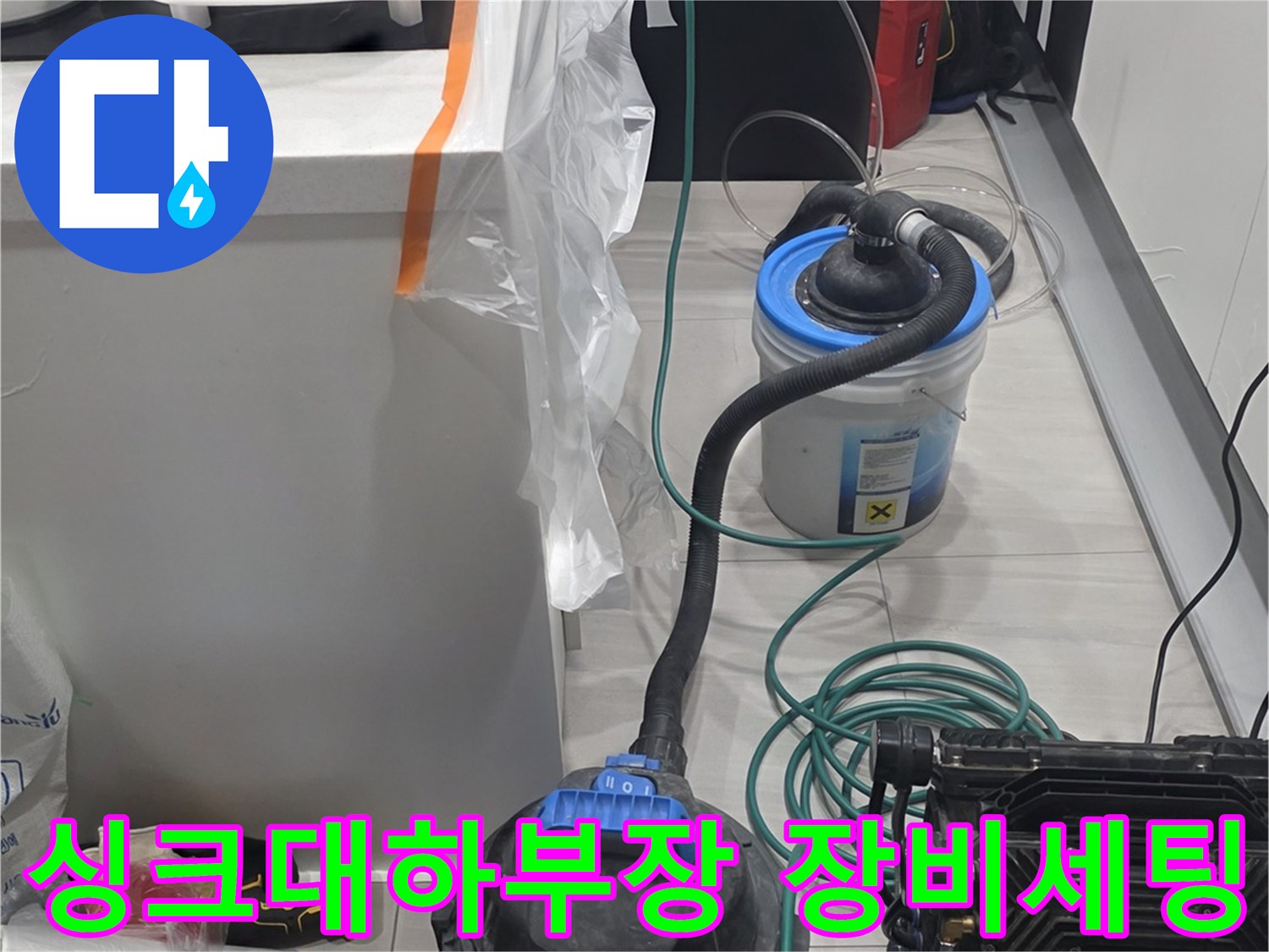 주방 싱크대 하단 작업 공간에 배치된 전문 탐지 장비와 청소 도구