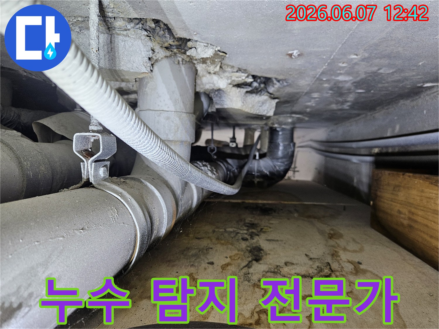 누수 탐지 전문가가-배관 주변에서 물이 새어 나와-바닥에 물자국이 생긴-현장을 진단하고 있습니다.