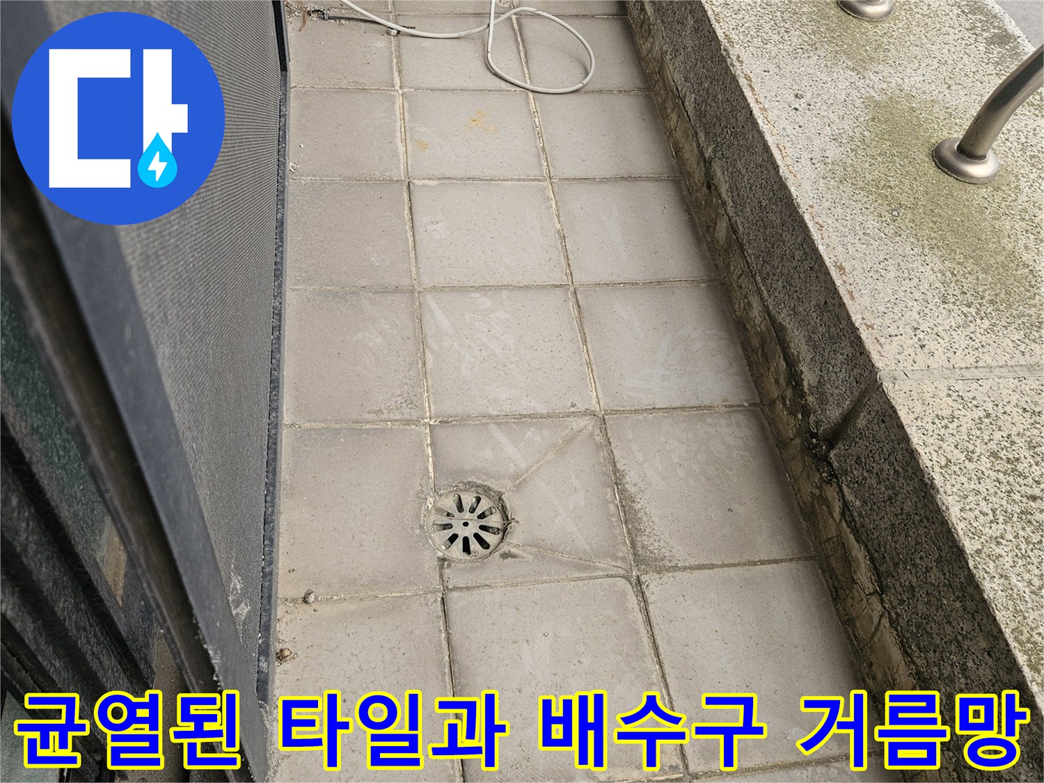 외부 테라스의 갈라진 타일 틈새와 중앙의 배수구 모습