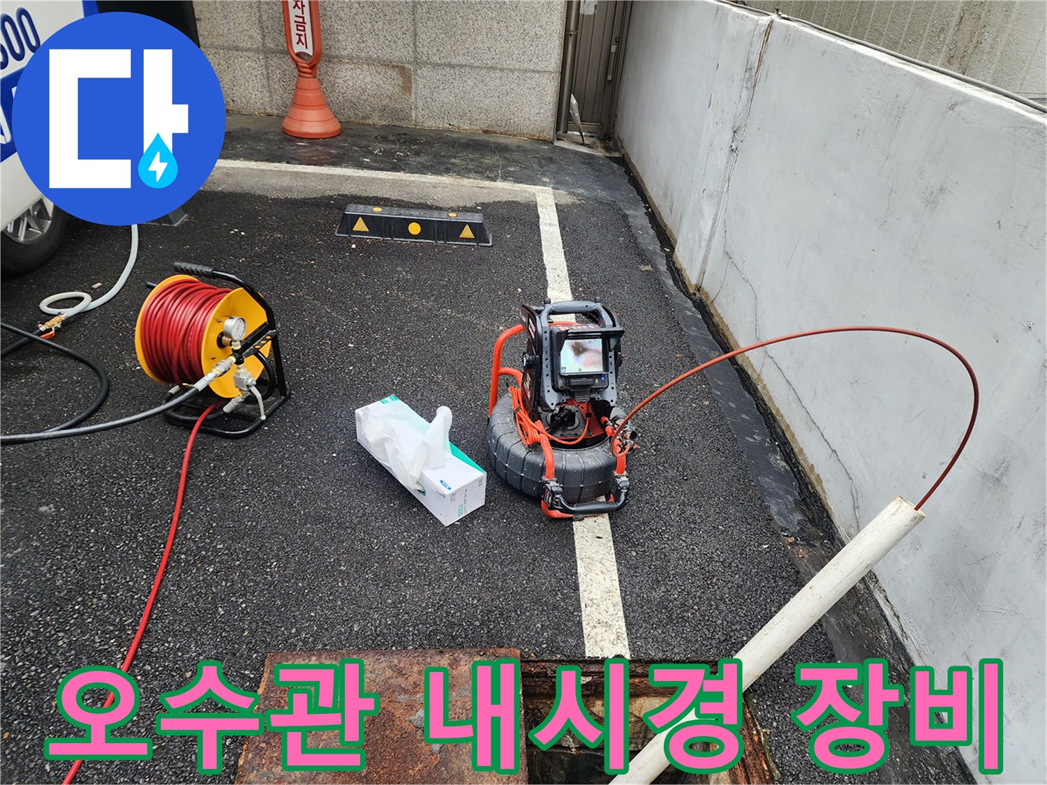 야외 맨홀 근처에 설치된 배관 검사용 내시경 카메라와 케이블 릴