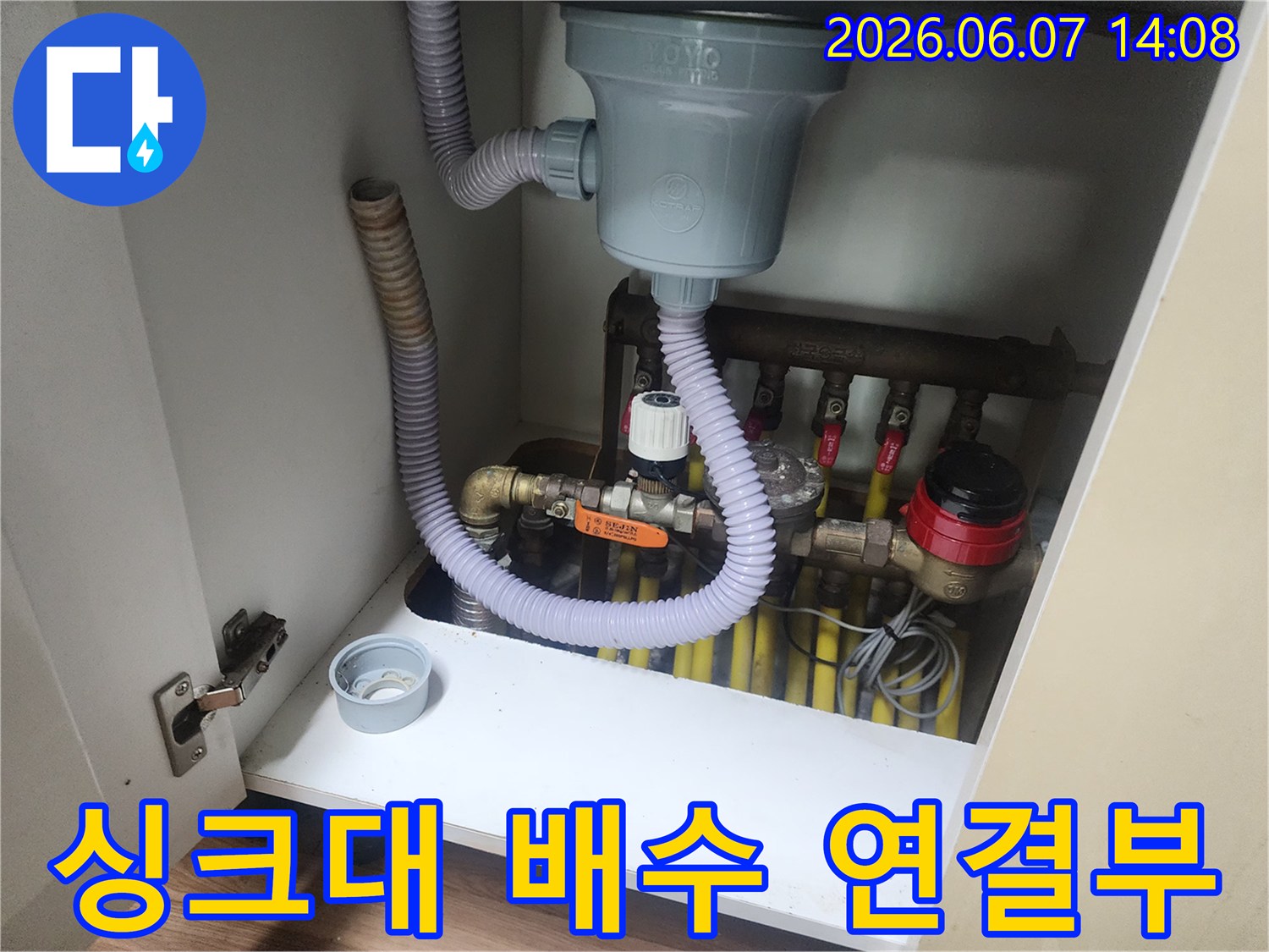 회색 주름관과 노란색 관-싱크대 아래쪽 배수 시스템의 복잡한 구조입니다.