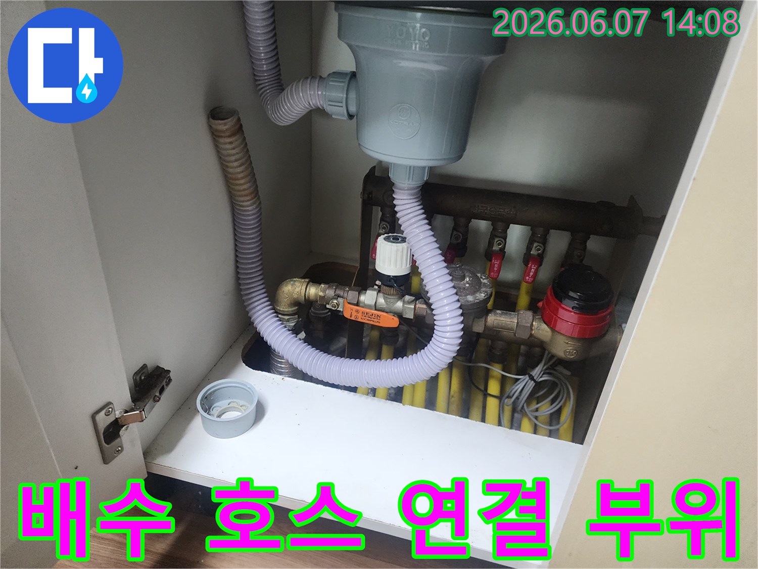 회색 주름관과 흰색 배수구가 연결된 싱크대 하단부 상세 사진입니다.