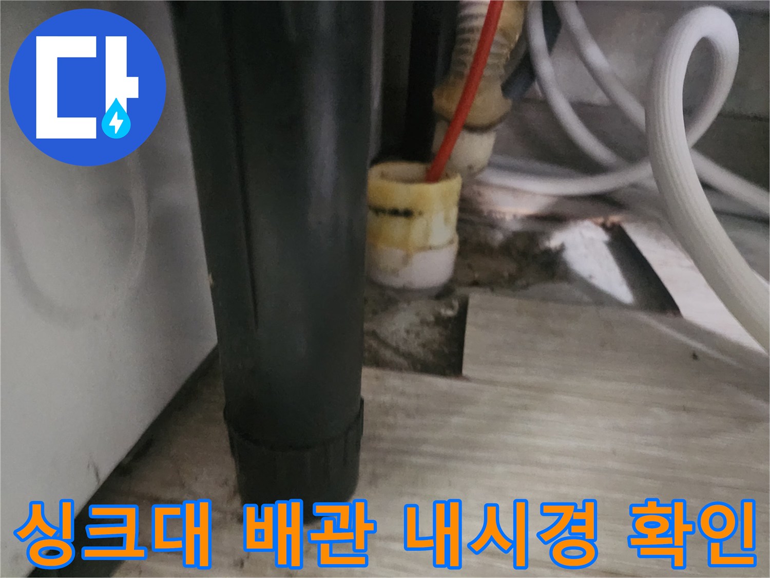 싱크대 하부 배관 틈으로 내시경 장비를 넣는 작업 장면