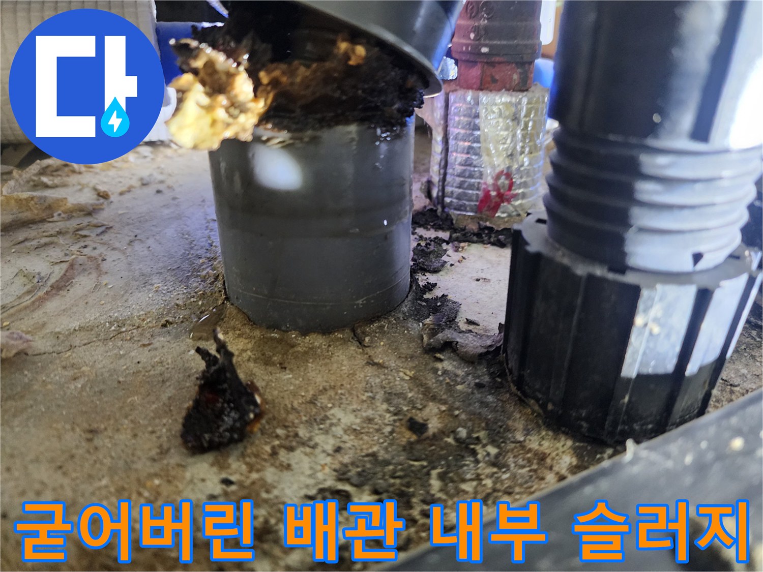 배수관 연결 부위와 바닥에 흩어져 있는 기름찌꺼기 잔해물