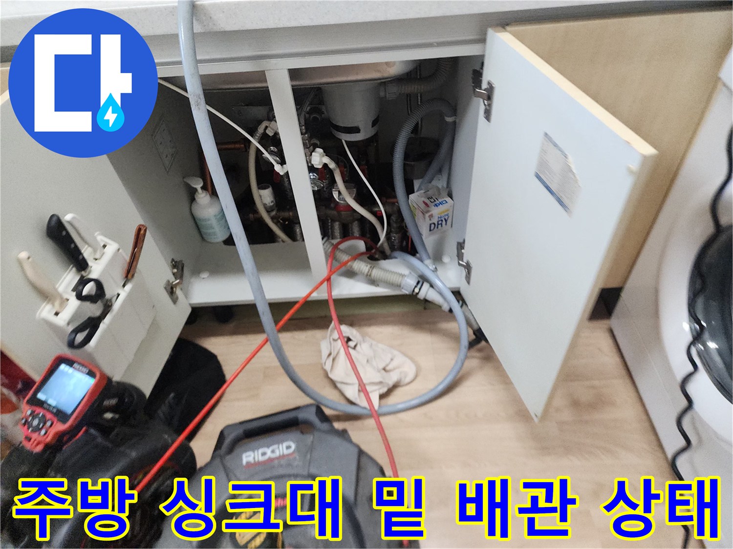 싱크대 하부장 내부의 젖어있는 바닥과 연결된 배수 호스들