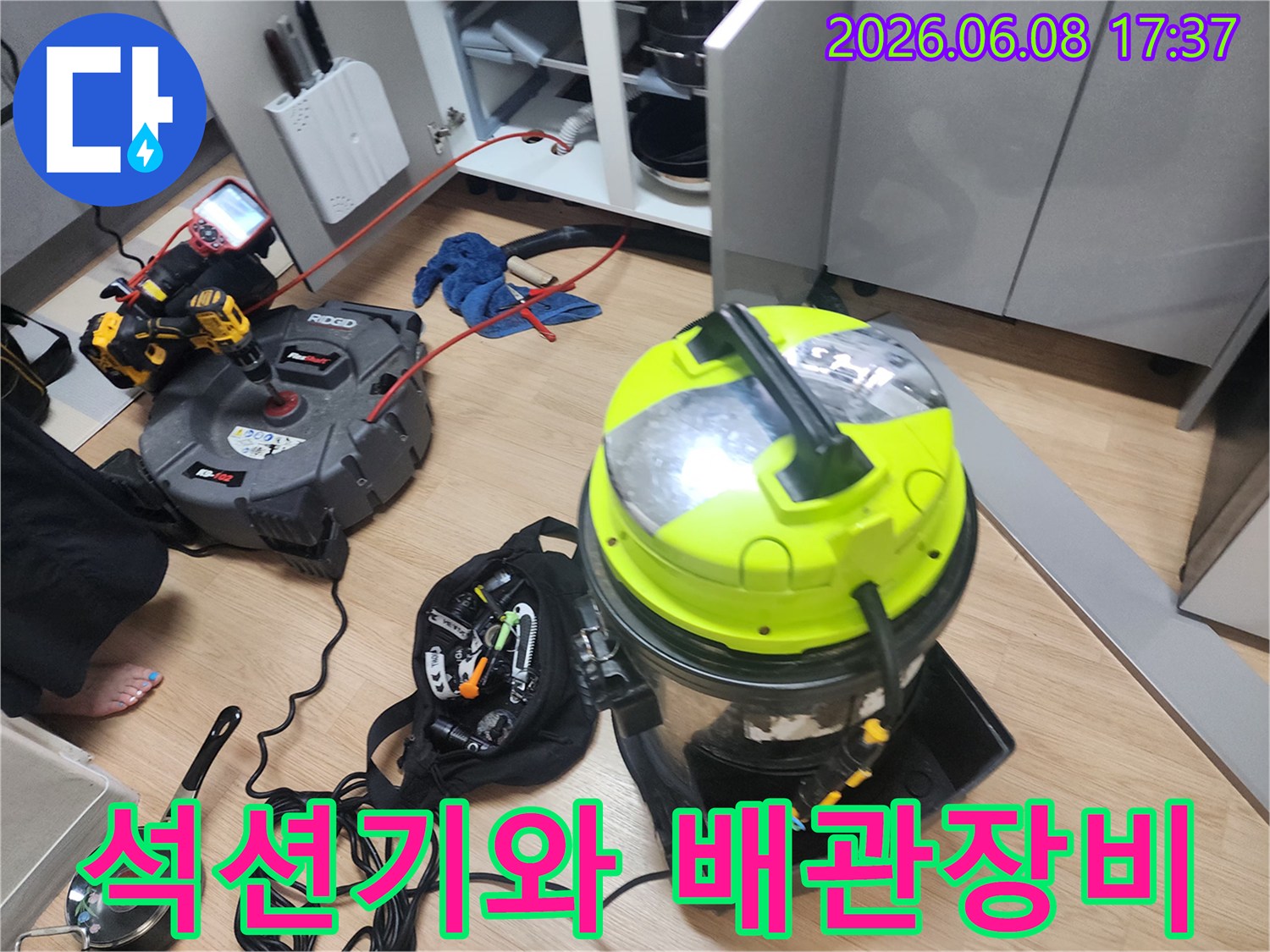 싱크대 하부장에서 작업 중인 전문 석션기 및 청소 장비 세트