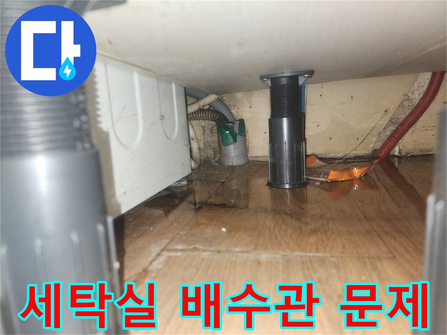 세탁기-아래-바닥에-물이-고여있는-모습으로-배수관-문제로-인한-누수-현장을-보여줍니다