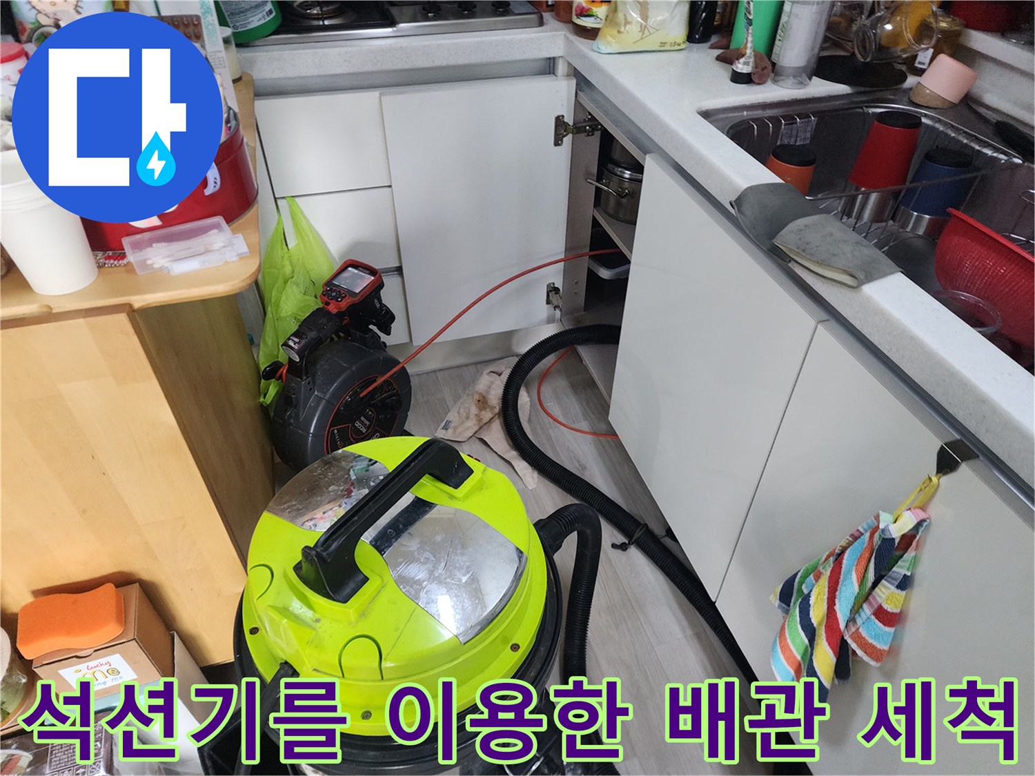 싱크대 하부 배관의 오염 물질을 제거하기 위해 석션 장비를 운용하는 장면입니다.