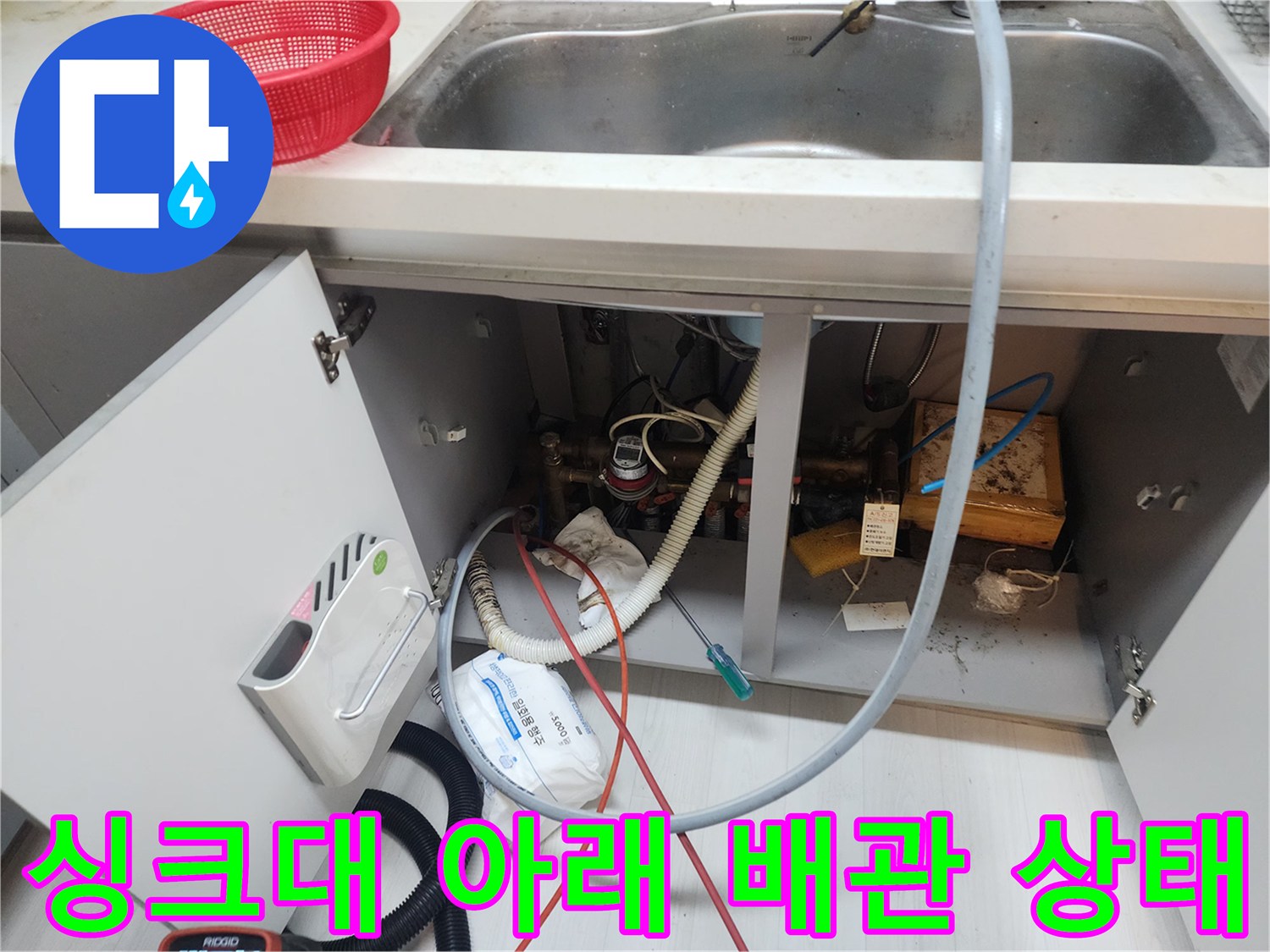 주방 싱크대 하단부의 복잡한 배관 연결 및 장비 세팅