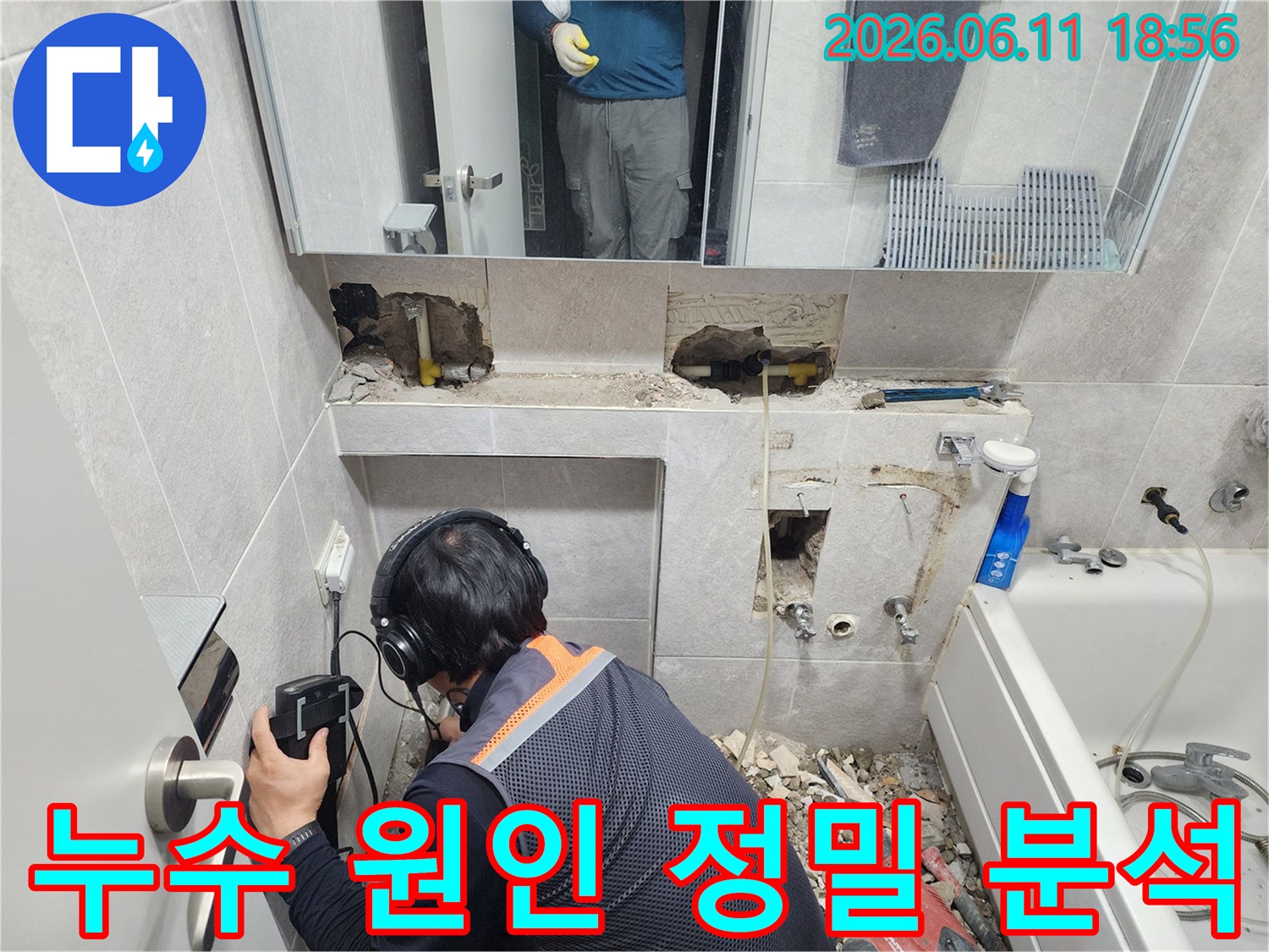 엔지니어가-특수 장비로-욕실 벽면의-누수 소리를 정밀하게 듣고 있는 작업 현장