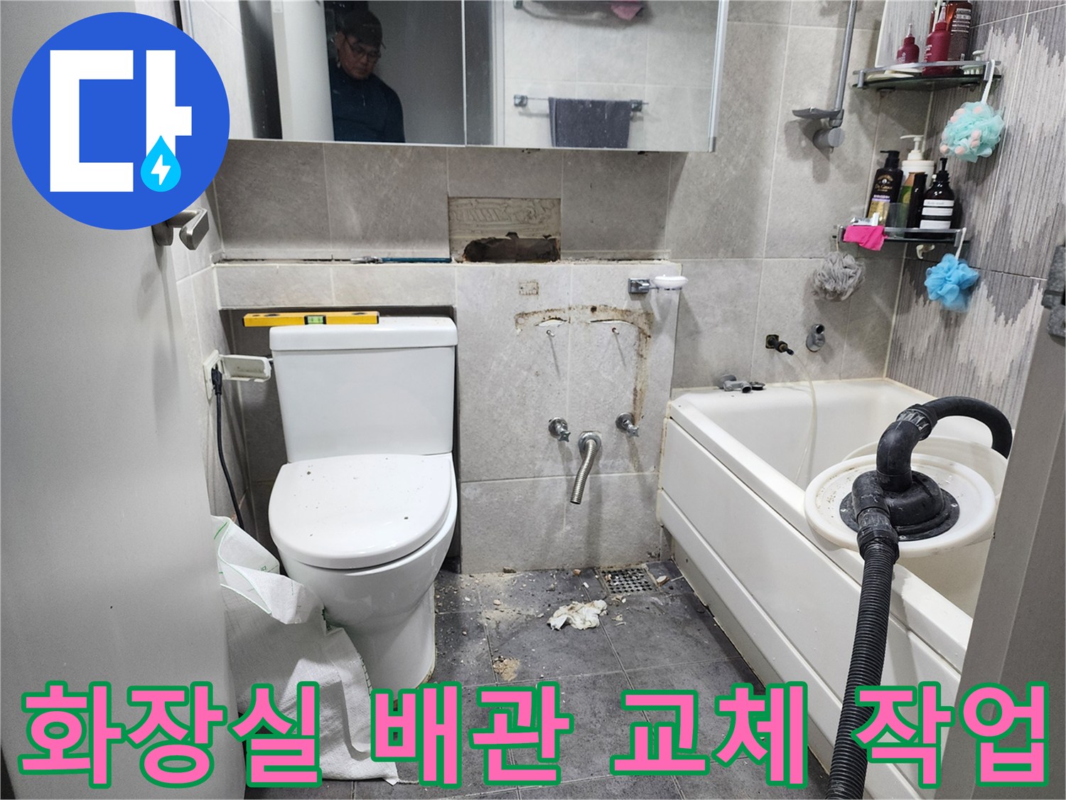 이 이미지는-동대문구 아파트 화장실에서-누수 원인인 낡은 배관을 교체하기 위해-기존 타일을 철거하고-새로운 배관을 설치하는-수리 현장을 보여줍니다