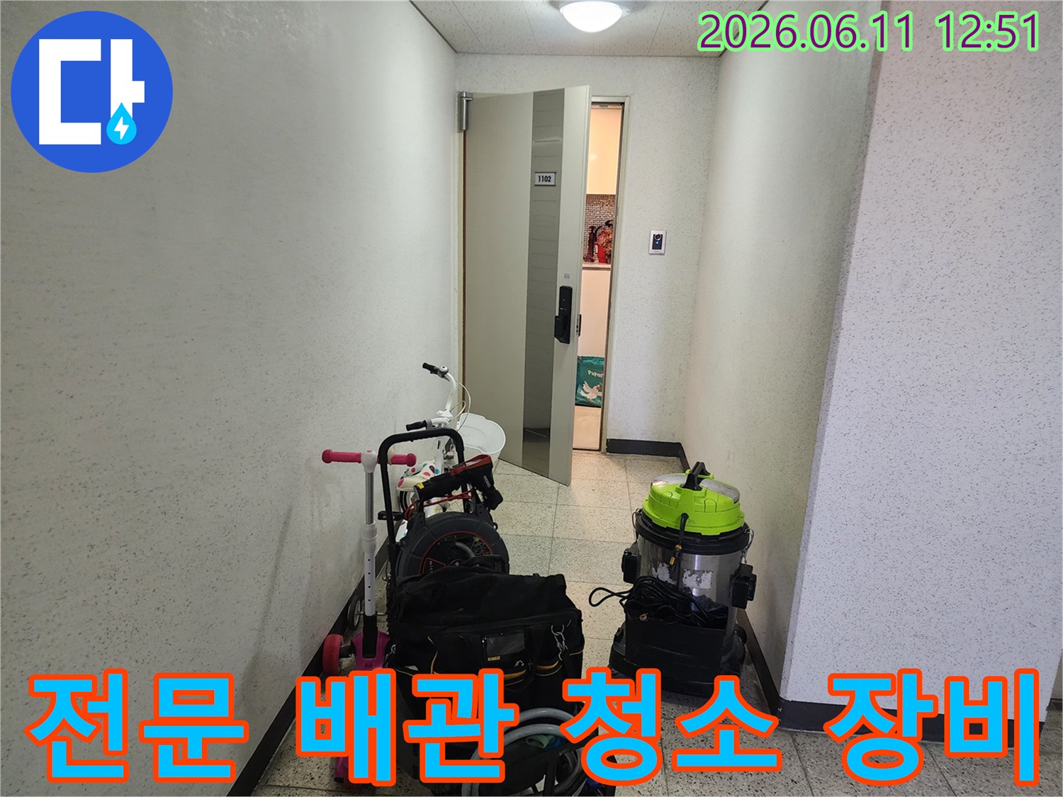복도 공간에 배치된 배관 청소용 진공 흡입기와 도구 가방입니다.
