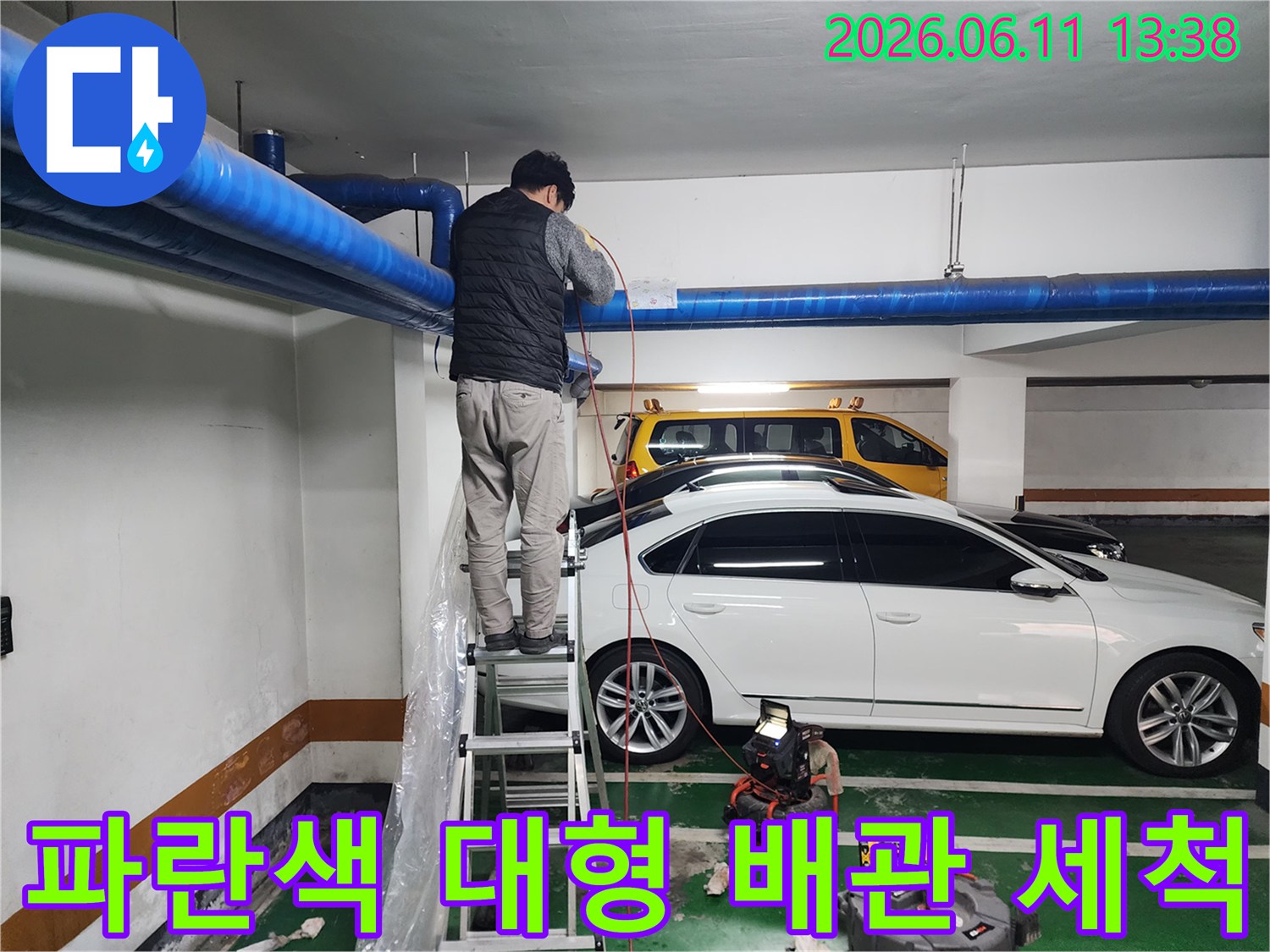 주차장 천장에 설치된 파란색 배관에 고압 세척 작업을 수행합니다.