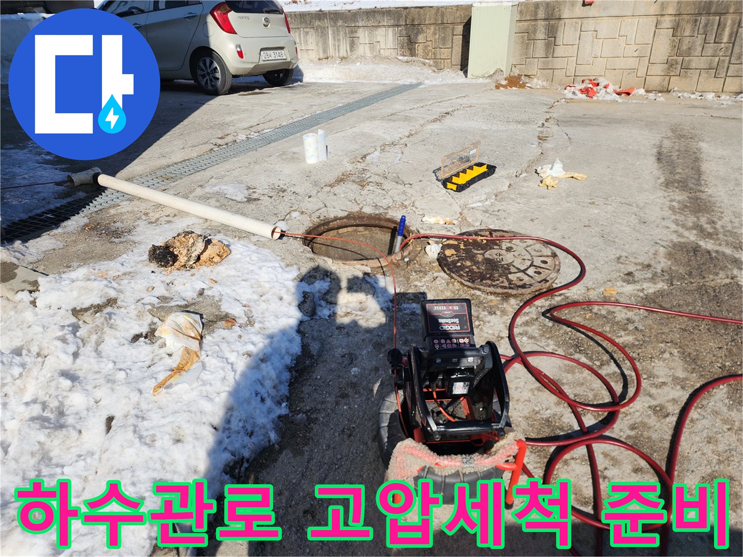 맨홀 인근에 배치된 전문적인 하수구 세척 장비와 호스들