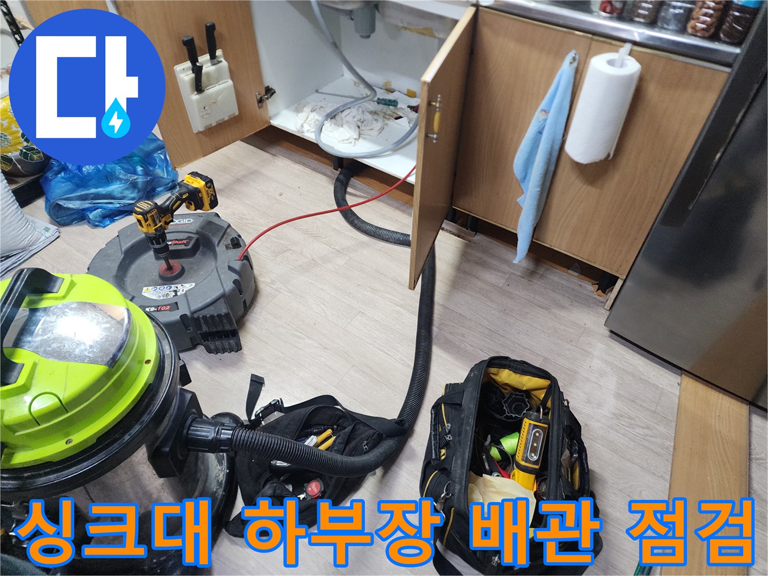 싱크대 아래쪽 배관 주변의 오염 상태와 작업 장비들