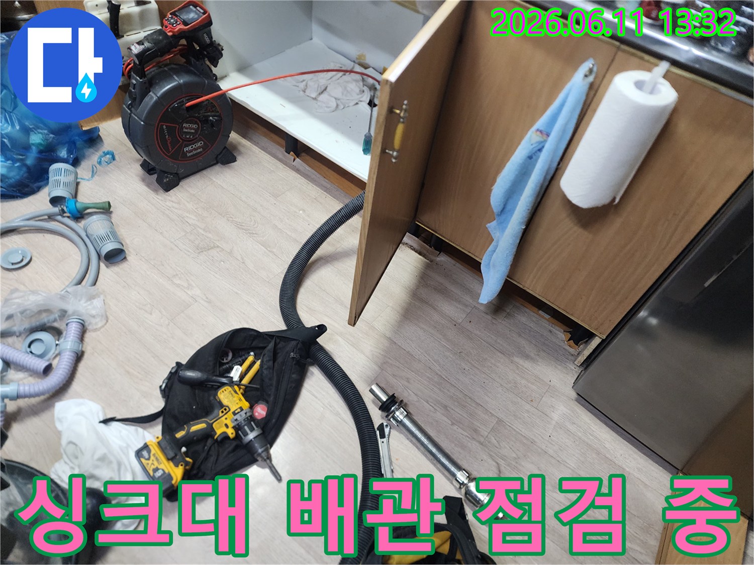 싱크대 하부장 내부의 막힌 배관을 청소하기 위한 장비 세팅 모습입니다.