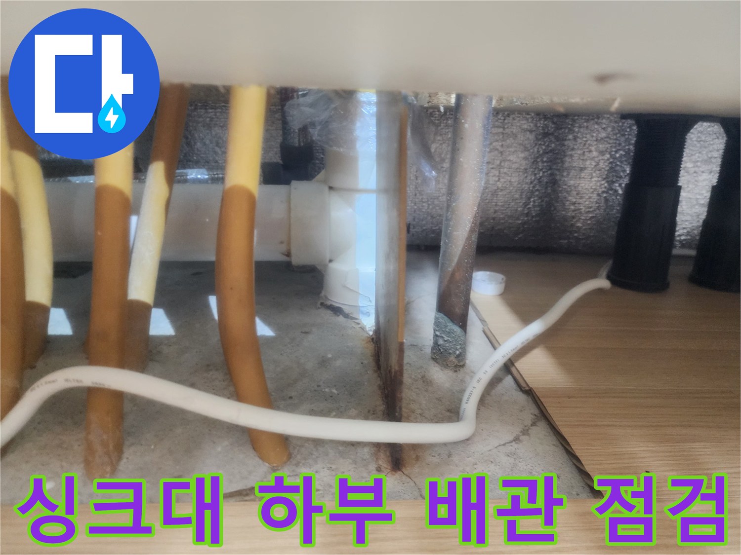 구리 갈매동 싱크대 하부장 내부의 노란색 배관과 바닥 배수구 상태를 촬영한 사진입니다.