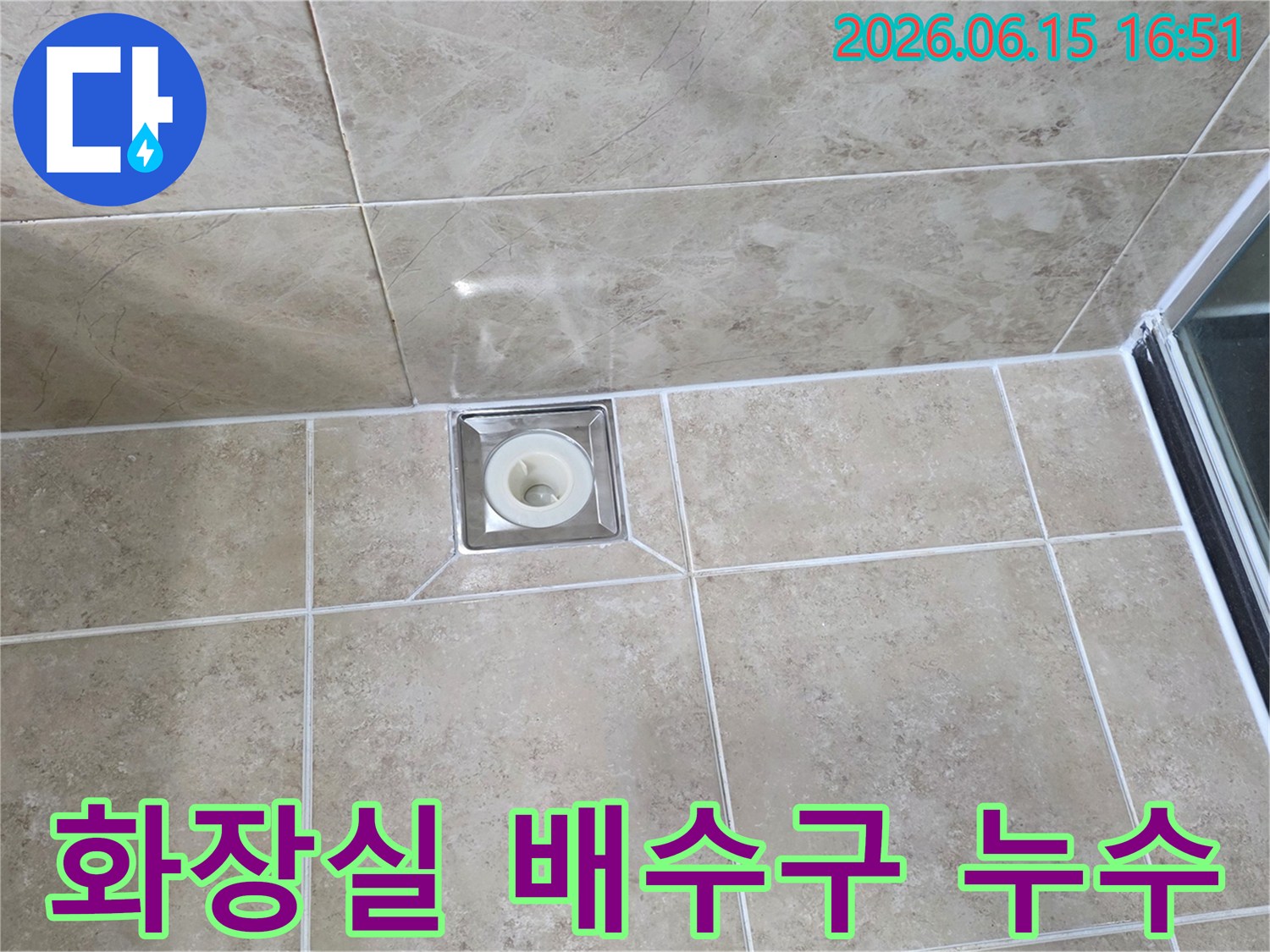 욕실 바닥에 설치된-사각형 스테인리스 배수구-주변 타일과 백시멘트 마감 상태를 보여주는 이미지입니다
