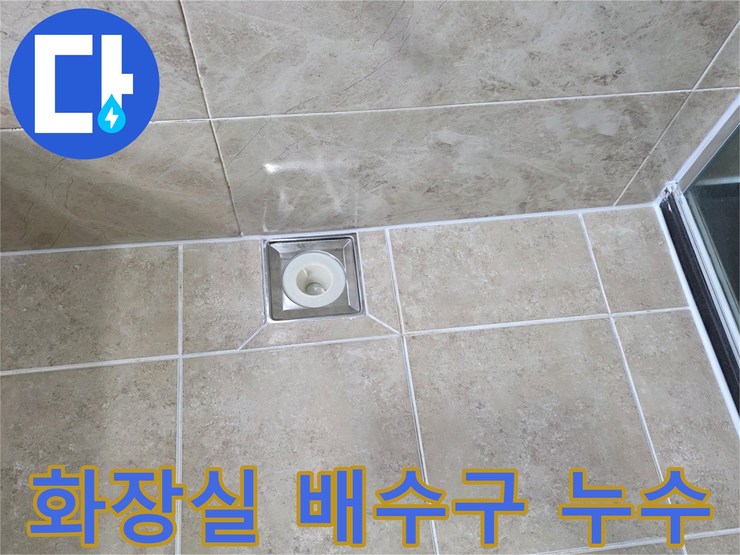 욕실 바닥에 설치된-사각형 스테인리스 배수구-주변 타일과 백시멘트 마감 상태를 보여주는 이미지입니다