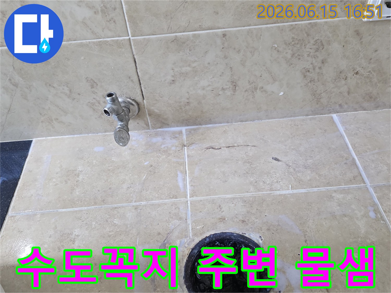 욕실 바닥에 설치된 수도꼭지와 배수구-주변 타일에서 발견된 물샘 흔적을 보여주는 이미지입니다