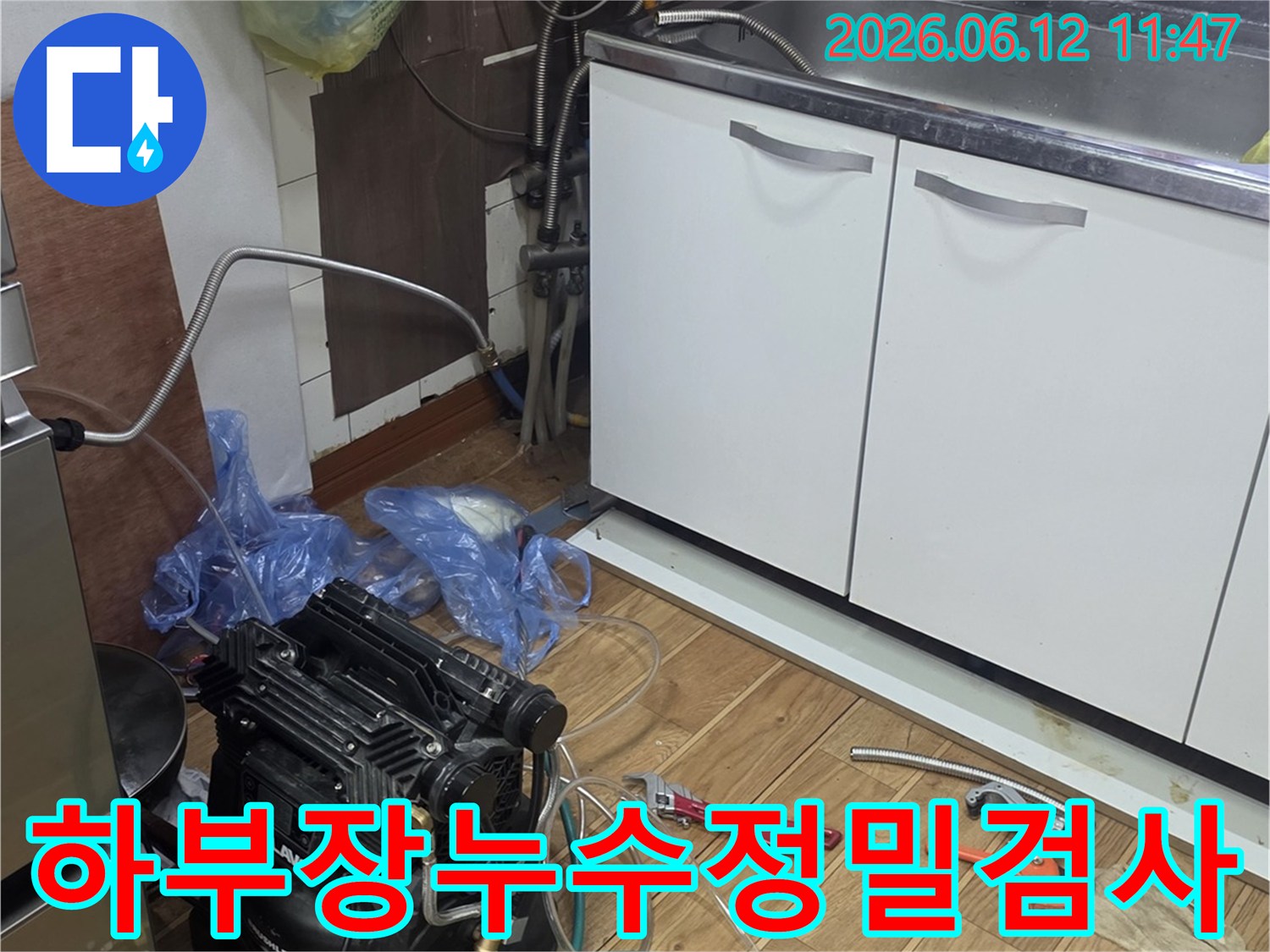 주방 싱크대 하부장에서-누수 탐지 장비를 연결하여-배관 상태를 면밀히 검사하는-전문가의 작업 현장