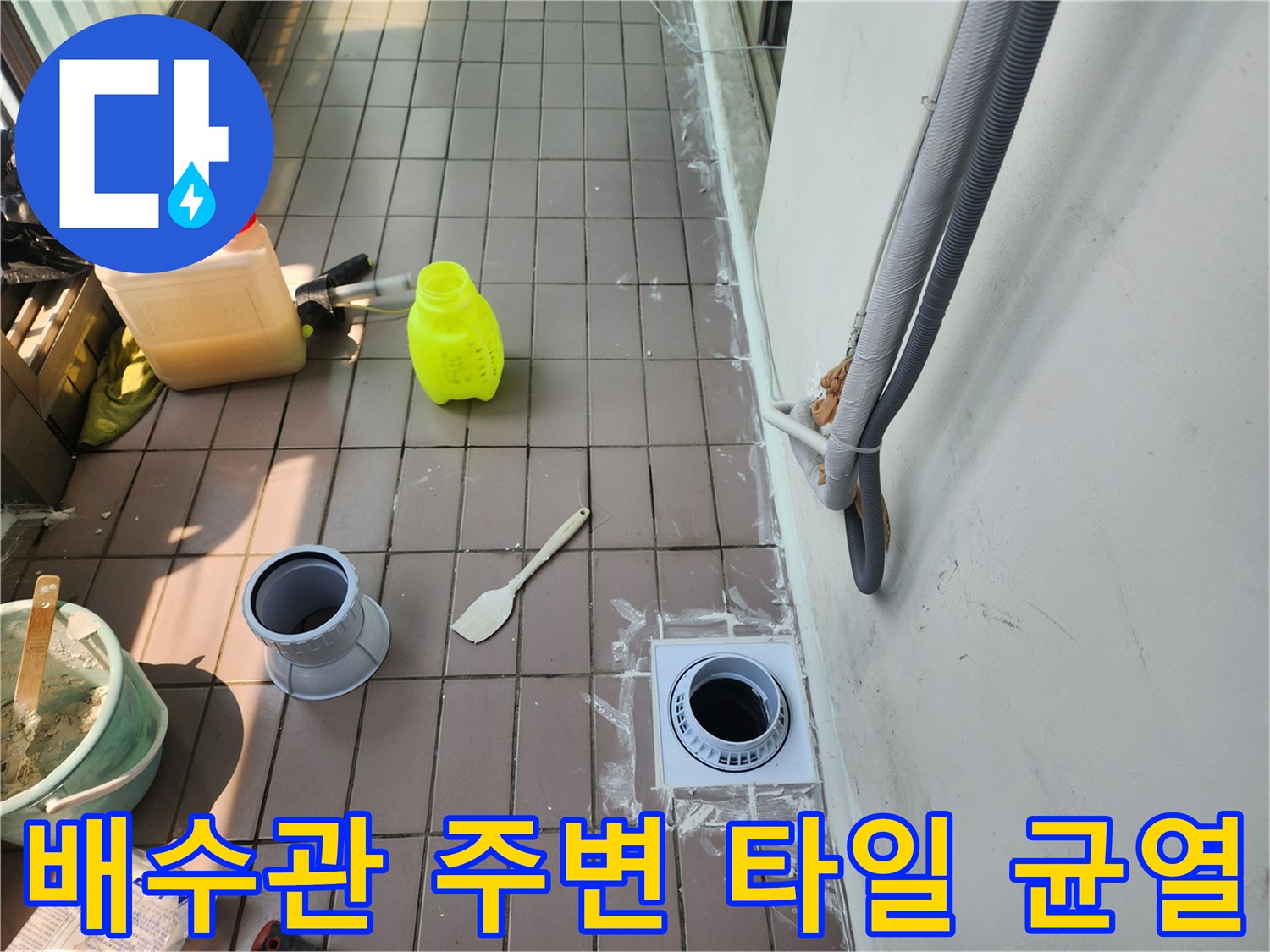 배수구가 설치된 베란다 바닥의 타일과 배관 연결 부위 상세 사진입니다.
