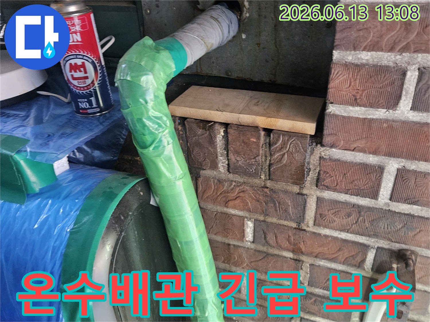 벽에서 나온 온수 배관의 손상 부위를-초록색 테이프로 감싸고 토치로 열처리하는 응급 조치 현장