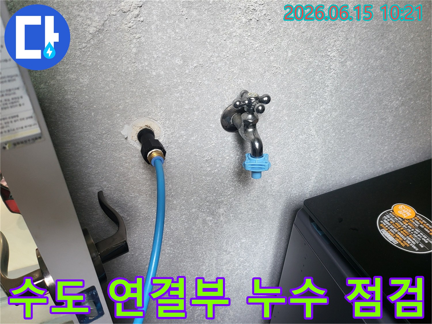 회색 벽에 설치된 수도꼭지와 파란색 호스-연결부의 누수 여부를 꼼꼼하게 확인하는 모습