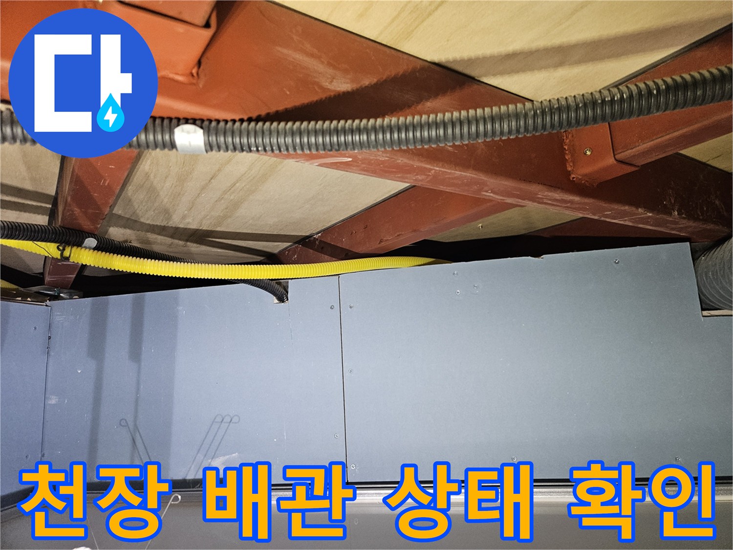 천장 내부의 붉은색 구조물과 노란색 주름관 배관 모습입니다.