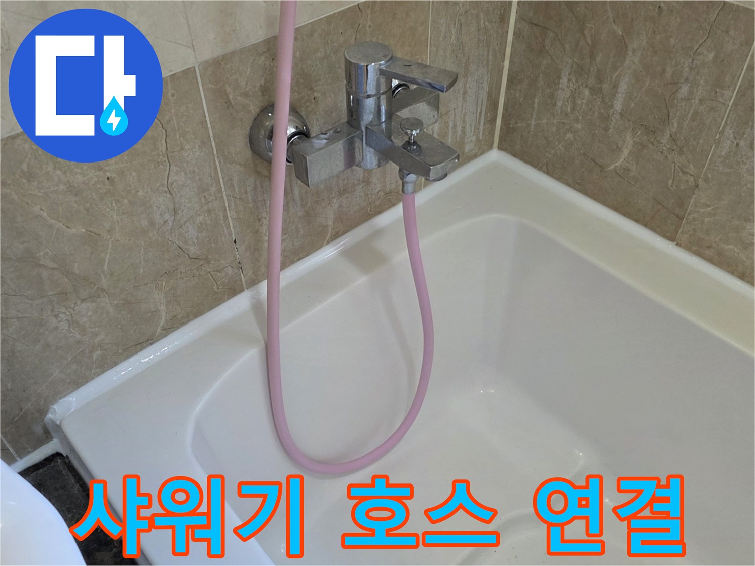 분홍색 샤워 호스가 연결된 욕조 수전의 근접 촬영 사진입니다.