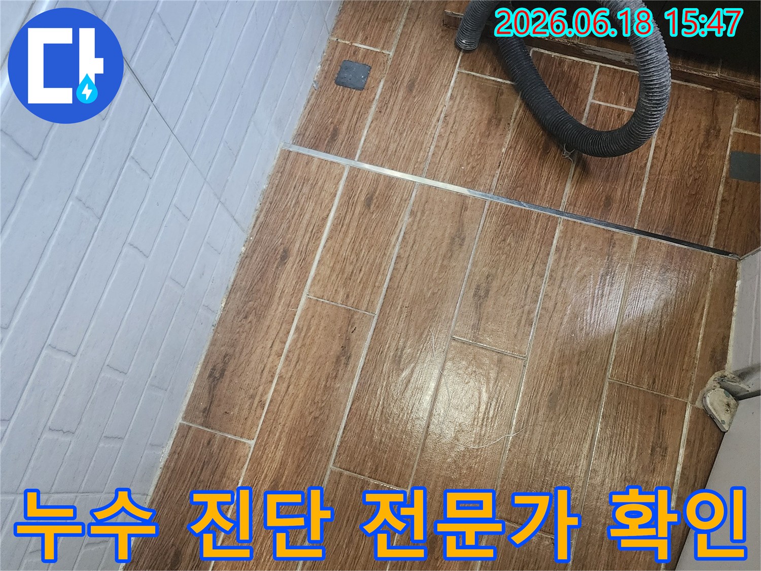 염창동 아파트에서 누수 진단을 위해 전문가가 현장을 방문하여 확인 중인 모습입니다-바닥 타일 위에 탐지 장비의 일부인 호스가 놓여 있습니다.
