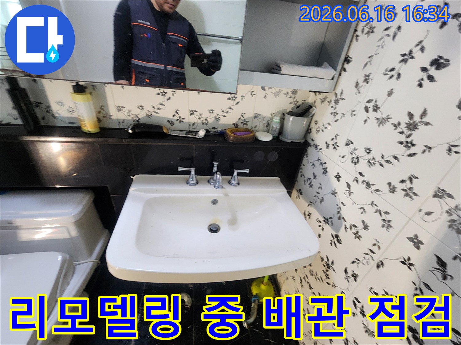 욕실 리모델링 작업 중-세면대 하부 배관의 누수 여부를-전문가가 꼼꼼히 점검하는-현장의 모습입니다