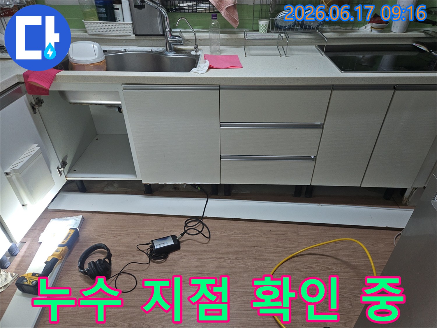 싱크대 아래에 물이 고이는 현상의-누수 지점을 확인하기 위해-전문 장비를 사용하여-하부 공간을 정밀하게 진단하는 모습