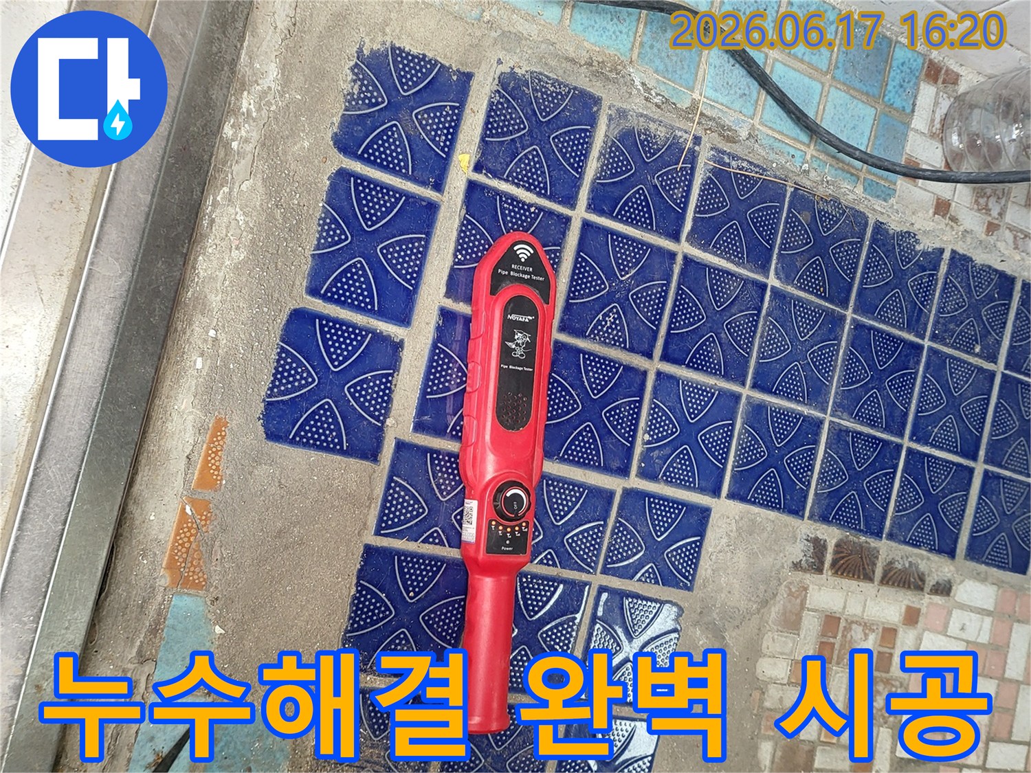 파란색 타일이 뜯겨나간 욕실 바닥에 놓인-붉은색 누수탐지 장비가-재발 없는 누수 해결을 위한 탐지 작업 중인 모습