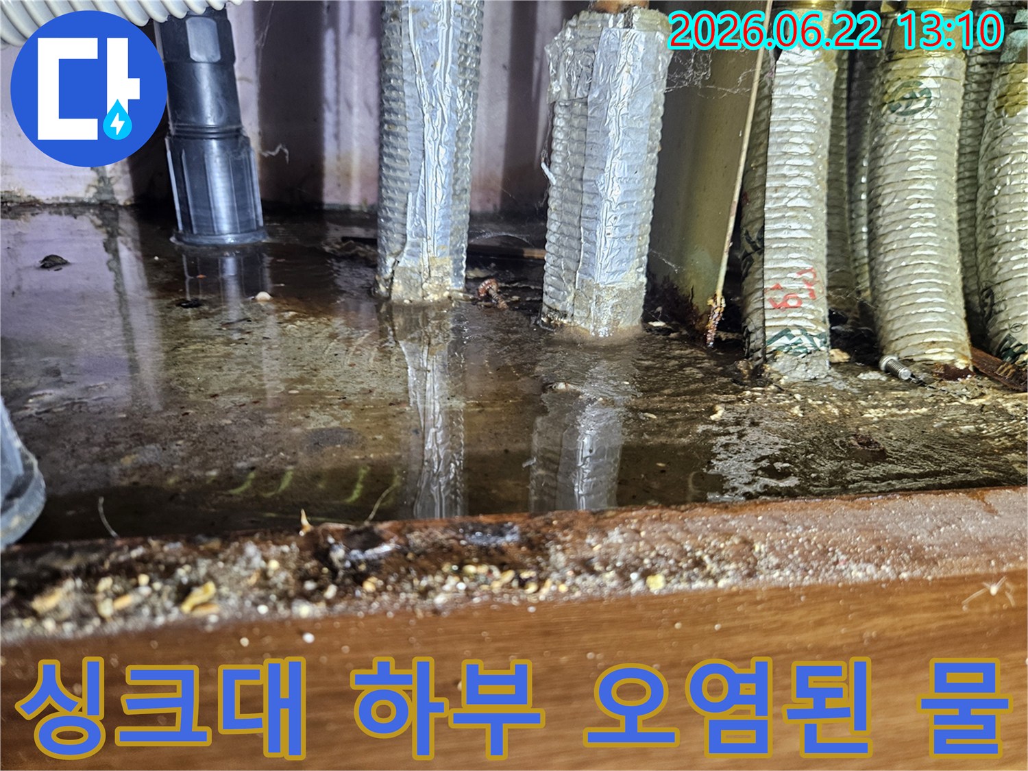 싱크대 하부에 오랫동안 고여-오염된 물과-배관 주변의 심각한 상태를 보여줍니다.