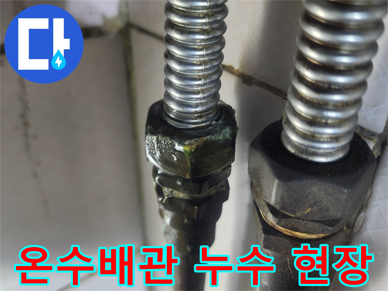 이 사진은 오래된 온수관 연결 부위에서 발생한-명확한 물방울과 부식 흔적을 통해-누수가 진행되고 있음을 보여줍니다.