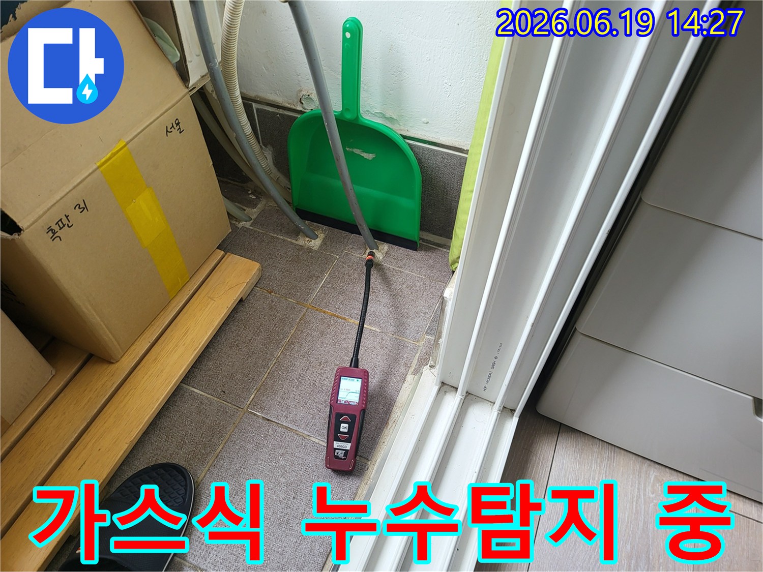 누수 탐지 전문가가-가스식 누수 탐지 장비를 활용하여-바닥에서 올라오는 미세한 가스를 감지하는 장면입니다.