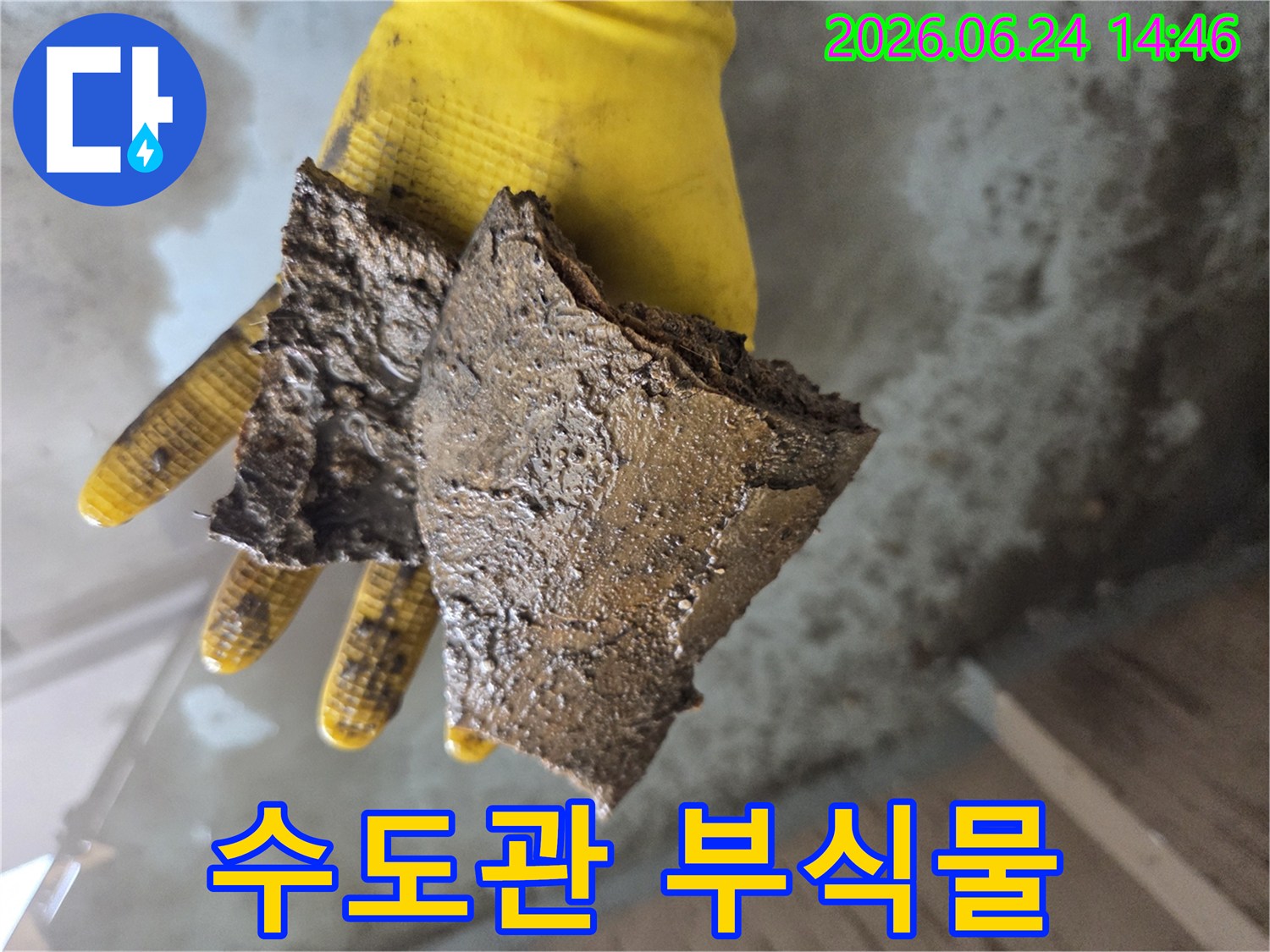 노란색-장갑을-낀-손이-오래된-수도관에서-나온-부식된-이물질-조각들을-들고-있는-모습